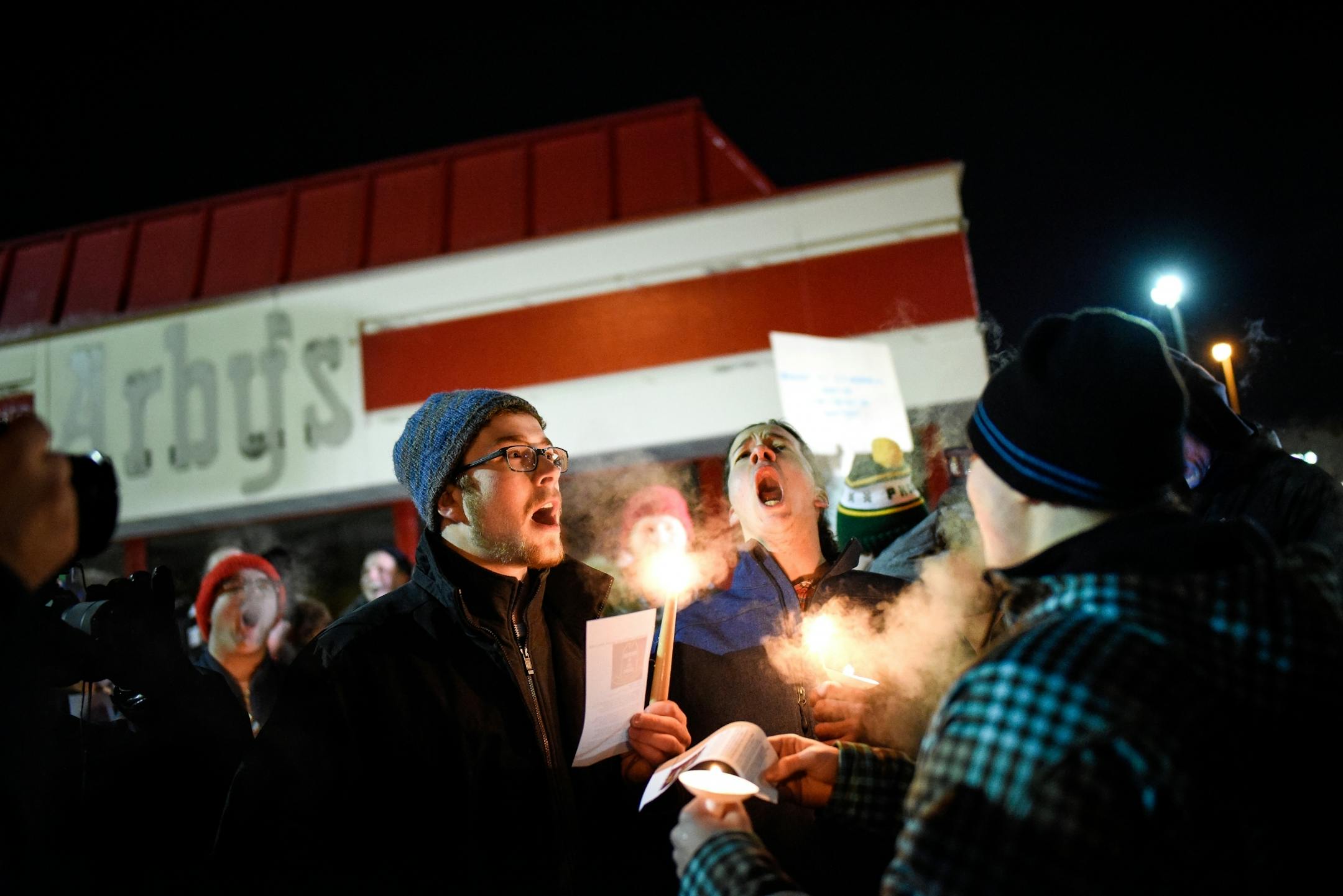 From left, Josh Nelson, of Crystal, Toby Sands, of New Hope, and Peter Holmquist, of Edina, belted out the words of an Arby's themed "Danny Boy" song written for Friday night's vigil.