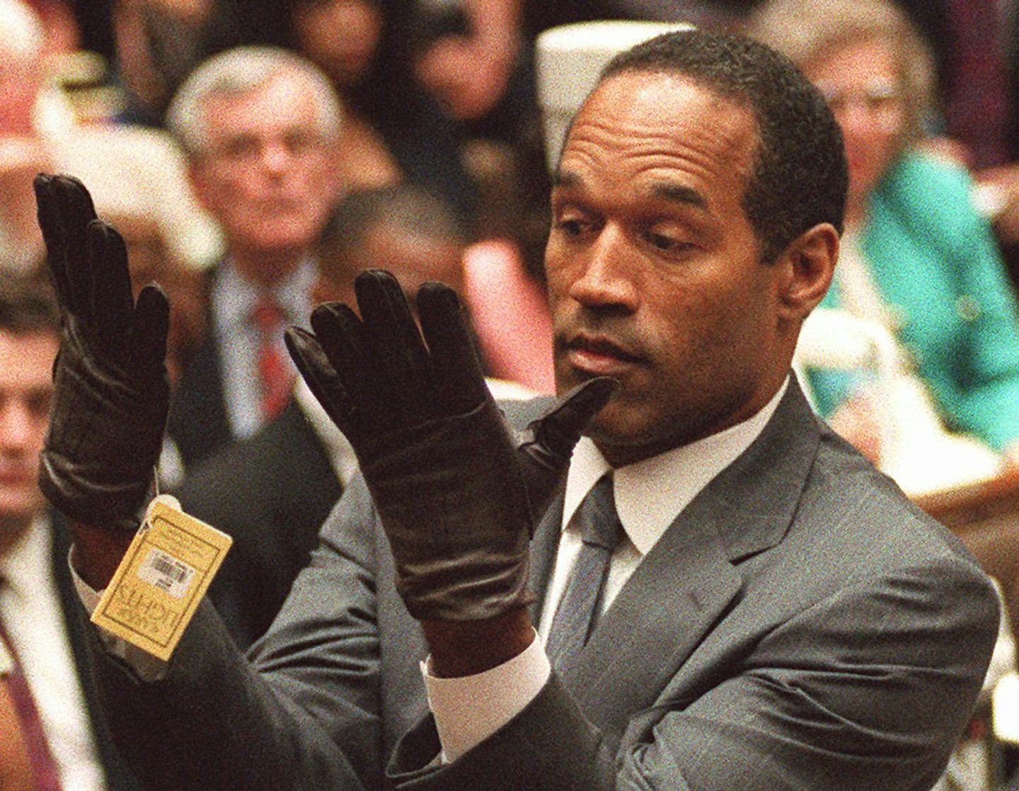 In this June 21, 1995 file photo, O.J. Simpson holds up his hands before the jury after putting on a pair of gloves similar to the infamous bloody gloves during his double-murder trial in Los Angeles.