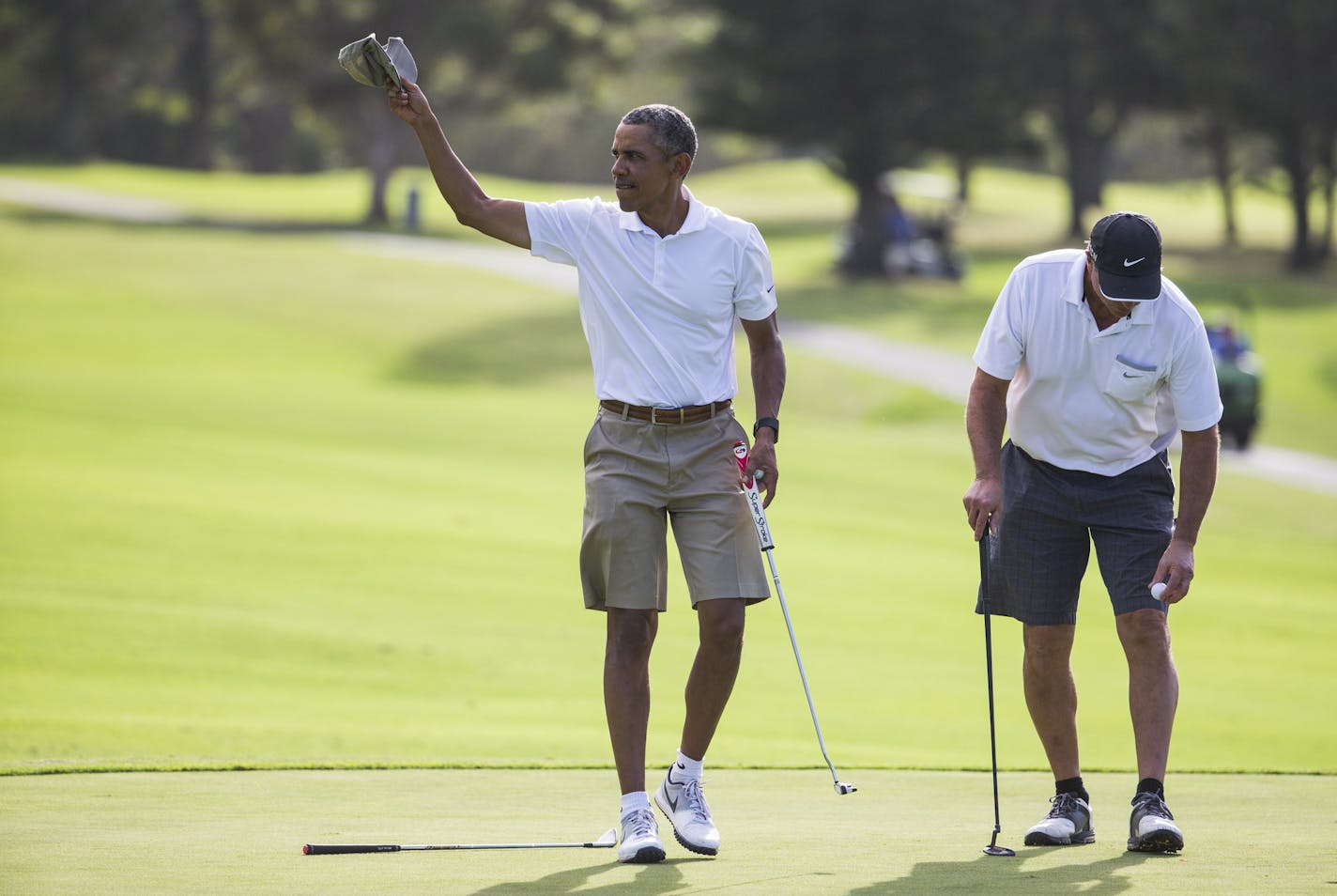 President Barack Obama tips his hat to the crowd after finishing a round of golf at Mid-Pacific Country Club during his family vacation, on Monday, Dec. 28, 2015, in Kailua, Hawaii. At right is Obama's friend Greg Orme. (AP Photo/Evan Vucci)