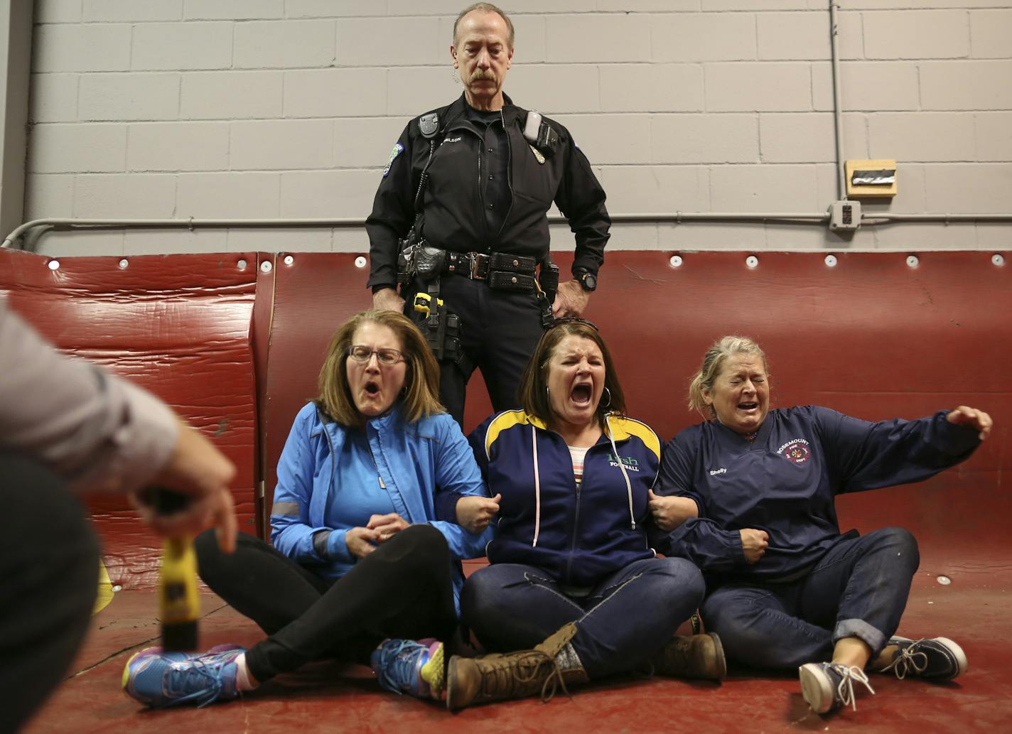 Judy Hayes, Alicia Blaz, and Shelly Anderson, from left, reacted to the jolt from a TASER held by Eagan Police Sgt. Rich Evans, left, during a demonstration Tuesday night at the Flint Hills Training Center. Eagan officer Tom Nelson stood nearby in case anyone reacted by falling backwards. ] JEFF WHEELER &#xef; jeff.wheeler@startribune.com Teachers from Dakota County schools have been getting a crash course in public safety from Rosemount, Apple Valley, and Eagan police trainers during the four s