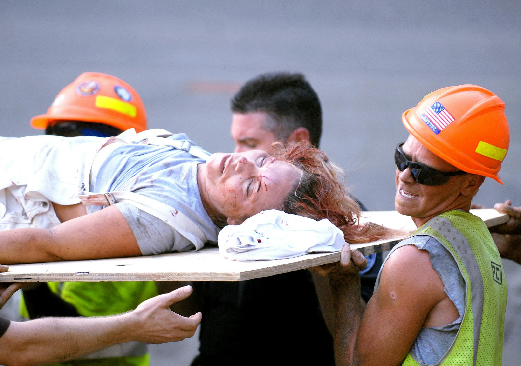 MUST CREDIT: Stacy Bengs/Minnesota Daily - August 1, 2007] Rescuers carry a gravely injured Paula Coulter off the bridge to a waiting ambulance. Matthew Miller is in the orange hardhat on the right.