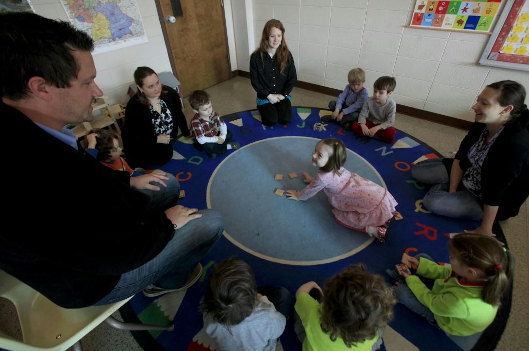 Klara Hankins, center, turned over wooden cards with pictures of animals on them as lead teacher Vincent Buettner, left, played a game with students in the Kinderstube German immersion preschool program. Assisting Buettner from Kinderstube were, from left, Katrina VanKempen, Robyn Carley and Doreen Brown.