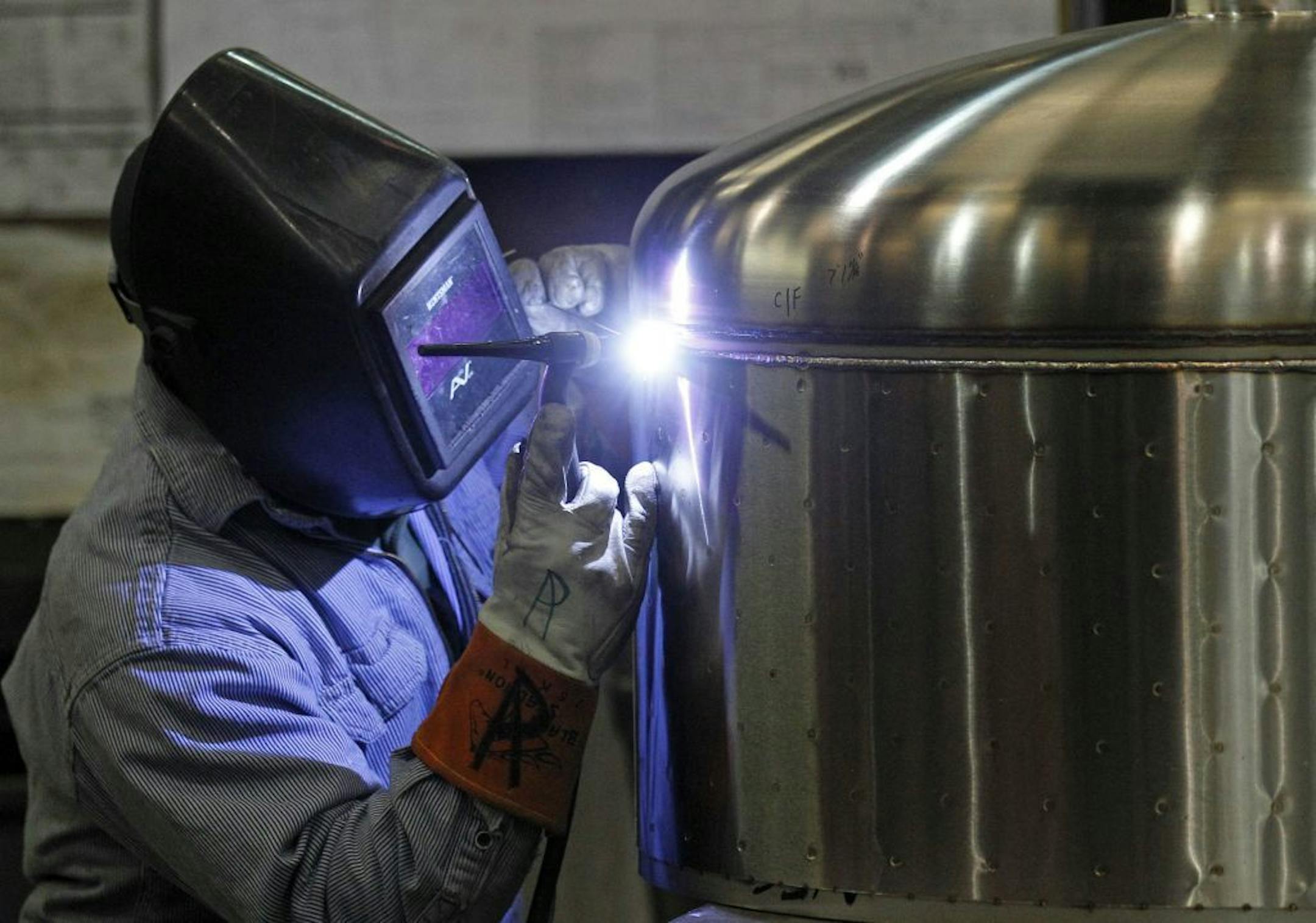 In this Dec. 14, 2011 photo, Kevin Offield makes a weld on a tank at JV Northwest, in Canby, Ore. JV Northwest manufactures stainless steel vessels. The number of people applying for unemployment benefits dropped to its lowest level since April 2008, continuing a downward trend that reflects a strengthening job market.