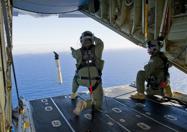 A handout photo of Royal Australian Air Force Sergeants Adam Roberts, left, and John Mancey launching a self locating data marker buoy from a C-130J H