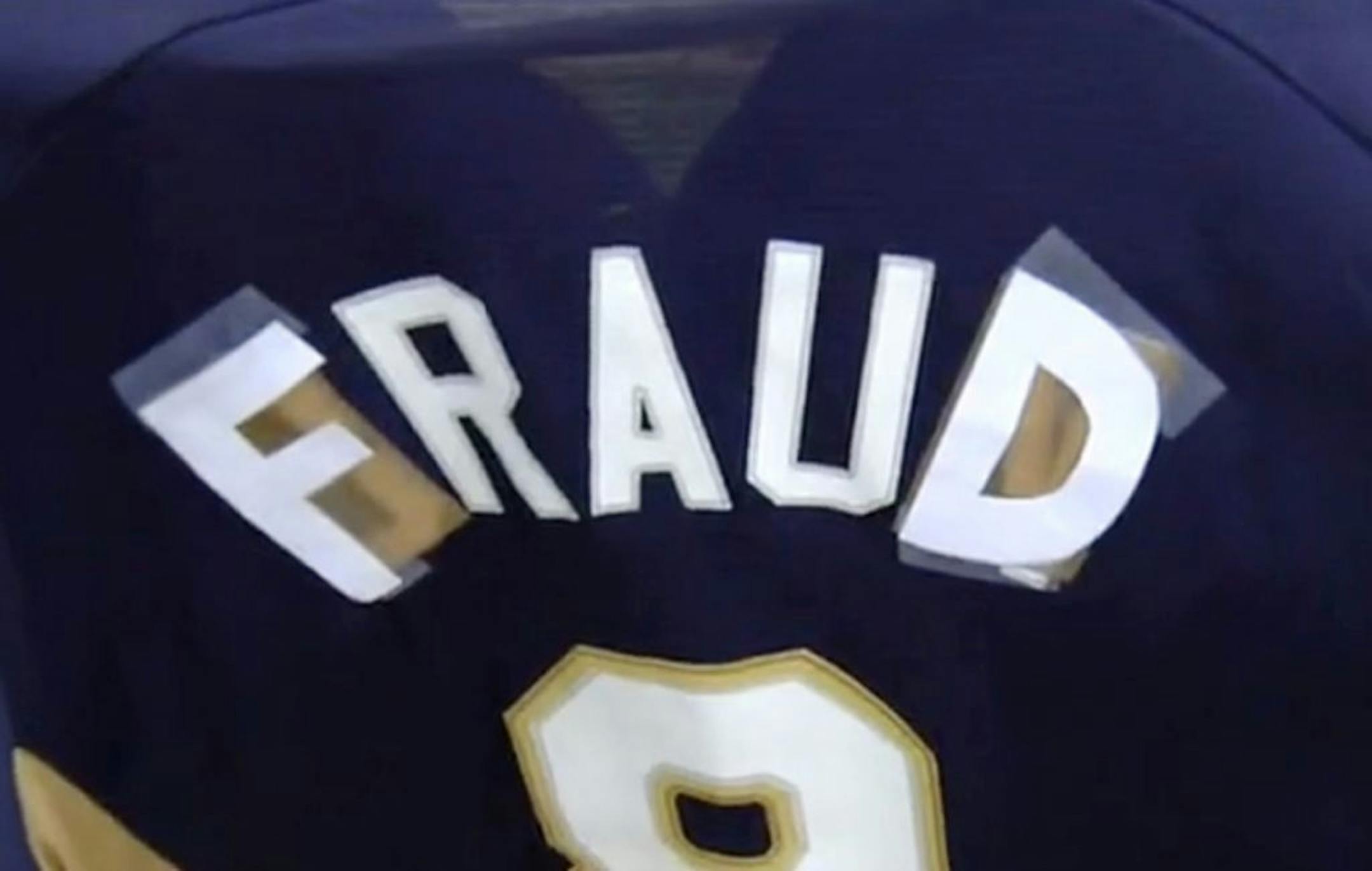 In this screen shot taken from a video released by TMJ4 in Milwaukee, Karen Eidem displays her Milwaukee Brewers jersey on Friday, July 26, 2013, in Milwaukee. The Brewers fan says she was asked to leave Miller Park because she had made some changes to her Ryan Braun shirt. Eidem said security tapped her on the shoulder while she was standing with friends at the ballpark Wednesday night. She had changed a couple letters on the back of her Brewers shirt to make it read 'Fraud' instead of Braun be