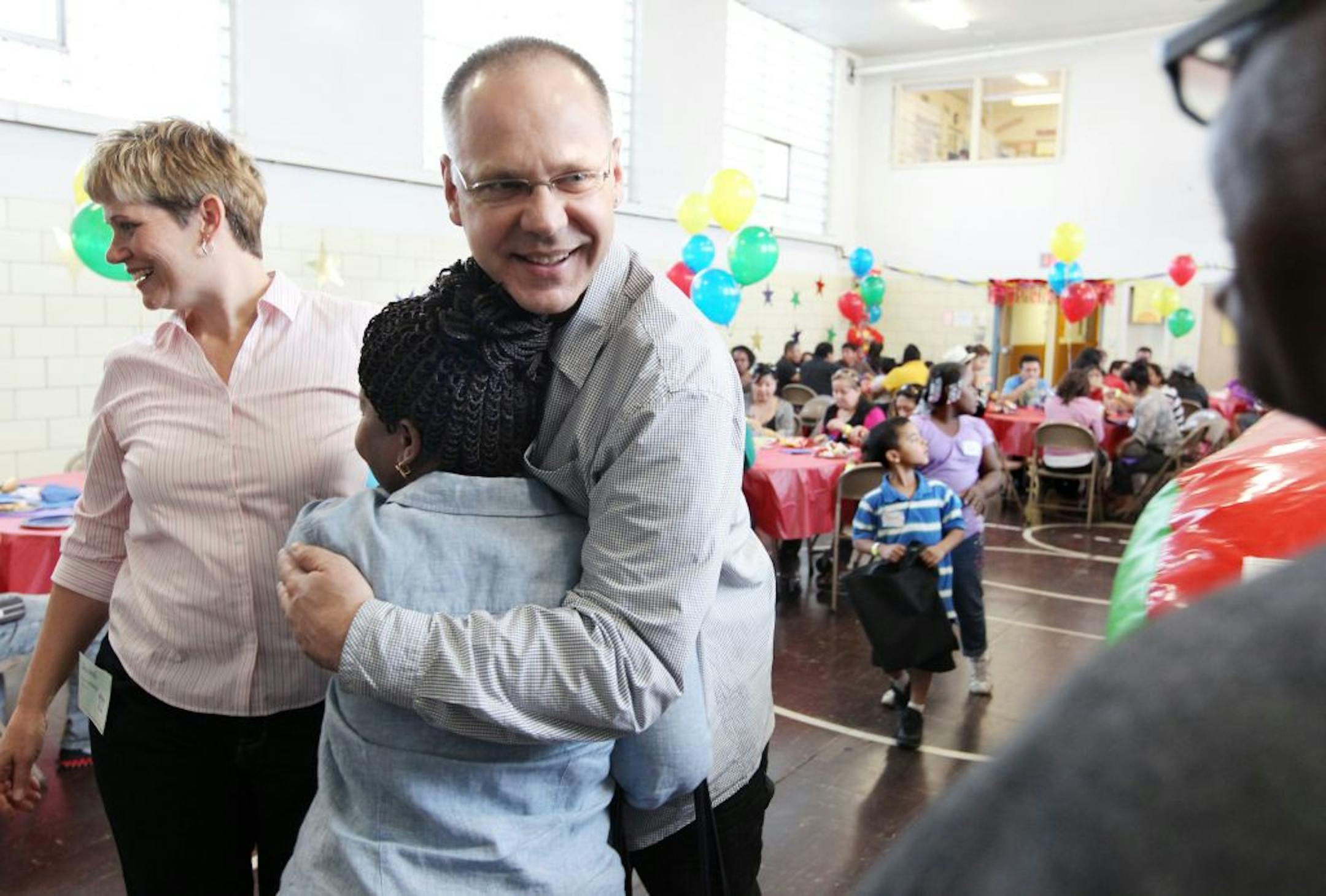 Tim Essenburg, center, hugs Toyin Olawole as he and his wife Joani Essenburg, left, greet people at the annual Banyan Community party in Minneapolis May 10, 2012. Olawole and her husband, Richard Olawole, far right, have a daughter who entered the Banyan program when she was in high school, and this spring she is graduating from The College of St. Scholastica.