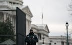 A U.S. Capitol Police officer guards a gate to the Capitol in Washington on Friday, Jan. 8, 2021, while wearing a black band over his badge to mark th