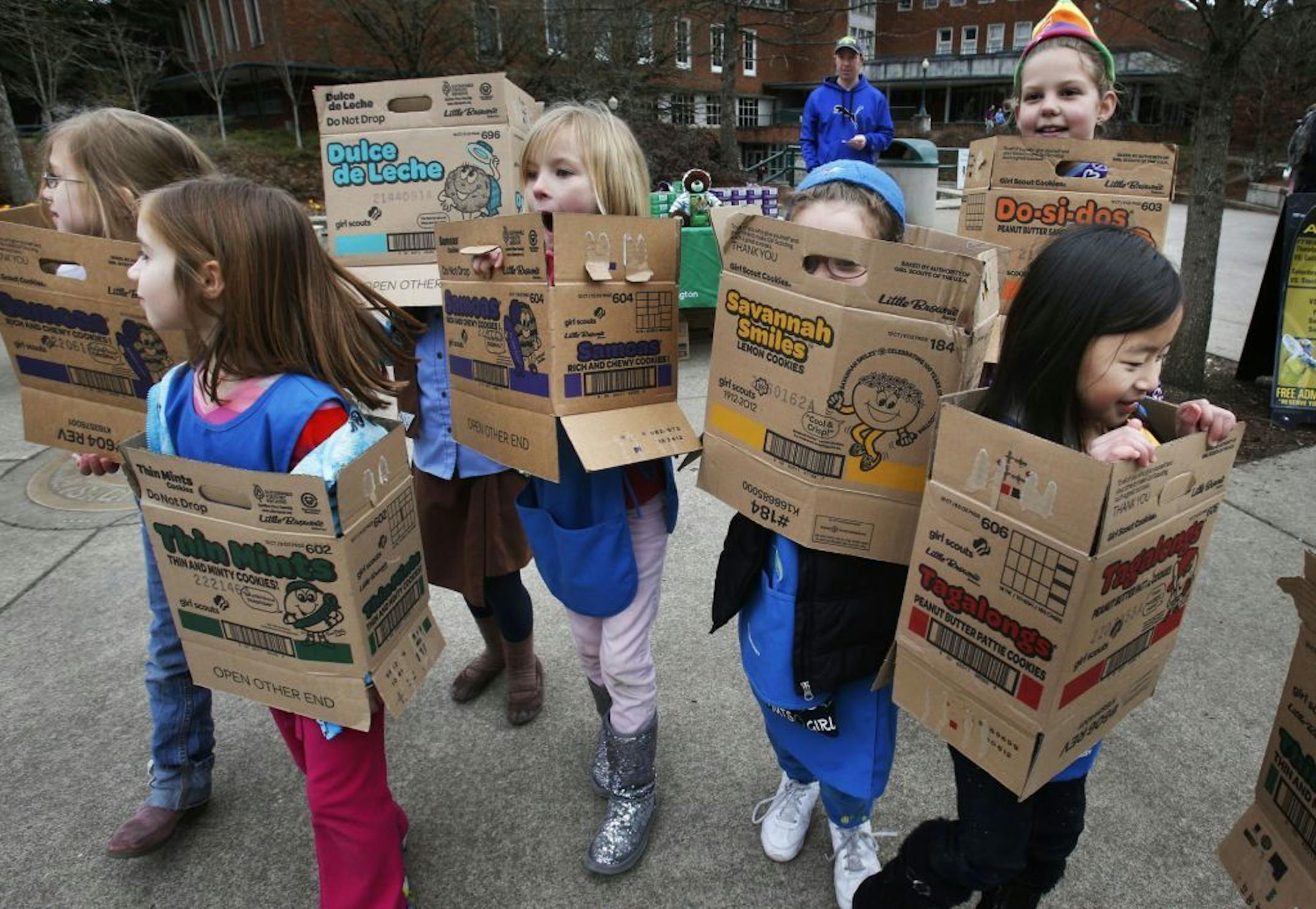 FILE - In a Feb. 18, 2013 file photo dressed in boxes emptied from earlier cookie sales, Girl Scouts from Troop 20337 in Eugene fan out on the University of Oregon campus near the Erb Memorial Union in Eugene, Ore., in search of customers for their cookies. Just a year after its 2012 centennial celebrations, the Girl Scouts of the USA's interconnected problems include declining membership and revenues, a dearth of volunteers, rifts between leadership and grass-roots members, a pension plan with