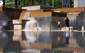 A young boy stopped playing briefly to have his photo taken in front of the fountains at Peavey Plaza as they flowed over the reflecting pool Thursday