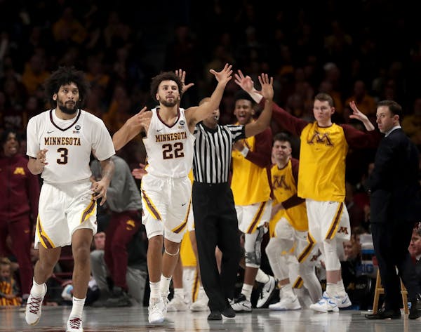 The University of Minnesota Gopher's Gabe Kalscheur (22) signals three, along with teammate Jordan Murphy (3), after he drained a shot from the corner