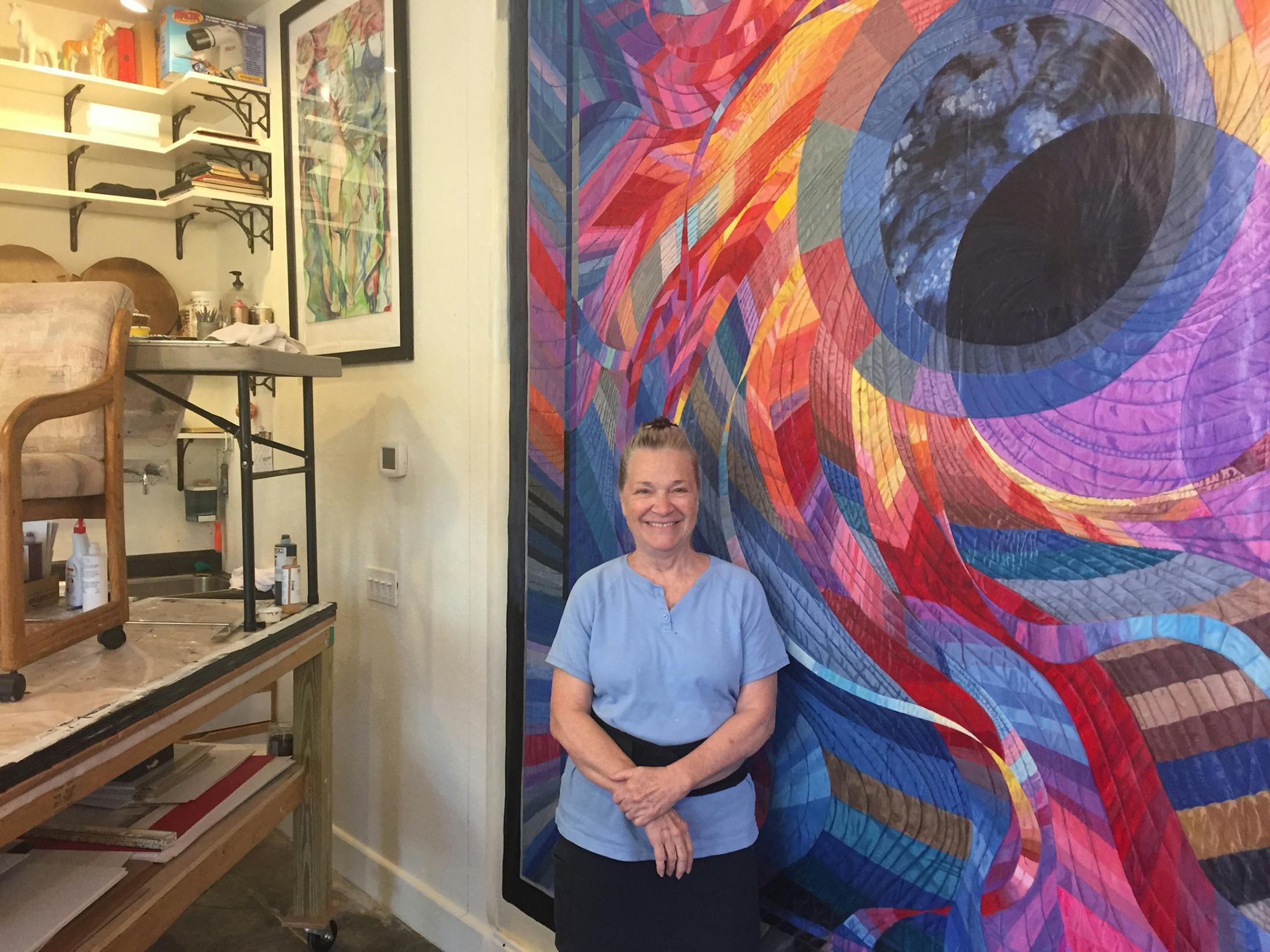 Artist Char Downs, who moved to Paducah from the San Francisco area as part of the city's artist relocation program, stands in her studio by her painting of Caryl Bryer Fallert-Gentry's quilt titled Corona II: Solar Eclipse. (Lori Rackl/Chicago Tribune/TNS)