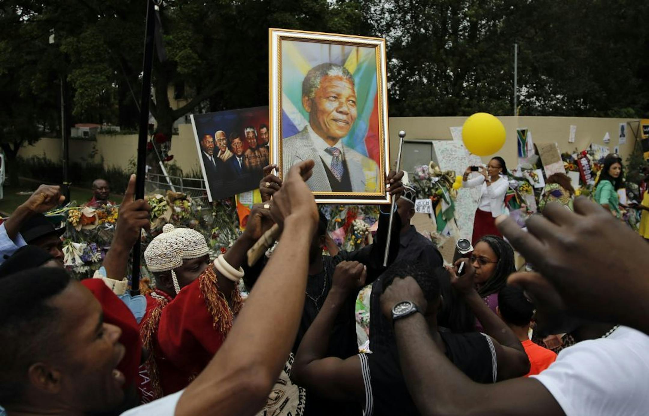 Mourners from Nigeria, sing outside the home of former president Nelson Mandela in Johannesburg, South Africa, Monday, Dec. 9, 2013.
