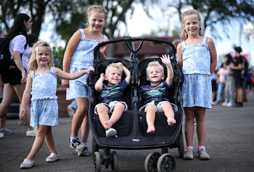 Sisters Ella, 9, Elizabeth, 7, and Ellison, 3, and their cousins, identical twin brothers Gavin, left, and Isaac, almost two, stand (and sit) near the Mighty Midway Sunday, Aug. 27, 2023 at the Minnesota State Fairgrounds in Falcon Heights, Minn. "We do this often," said the twins' father, Max. "It's always the moms" who plan it.