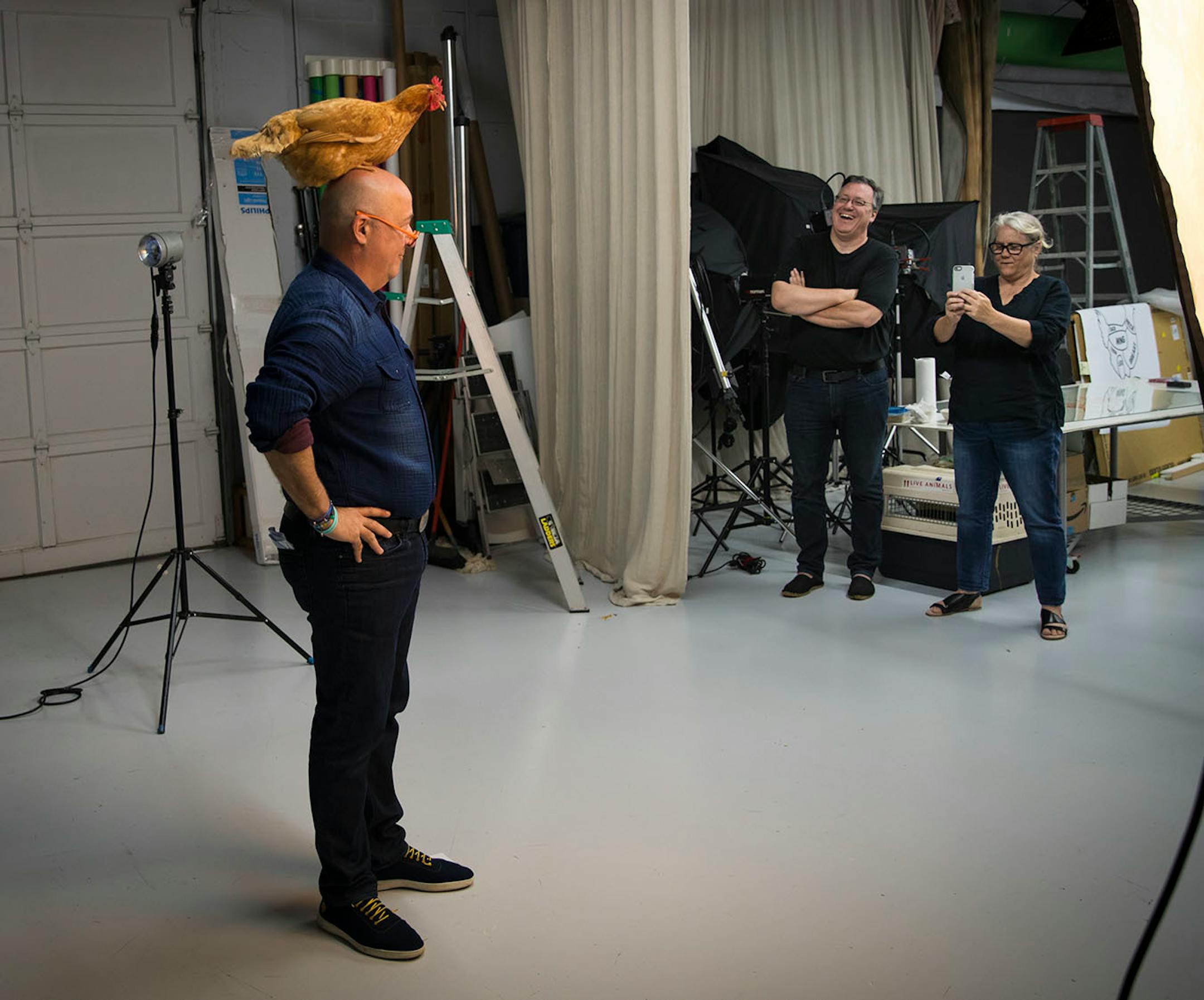 Andrew Zimmern posed with a hen as the hen's owner Steve and Mary Jo Hoffman watched from the side during a photoshoot for a Midwest Living story at photographer Steve Henke's studio in Golden Valley, Minn., on Friday, May 26, 2017.