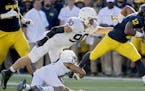 Penn State's Jordan Smith and Garrett Sickles try to stop Michigan running back Chris Evans during an NCAA college football game in Ann Arbor, Mich., 