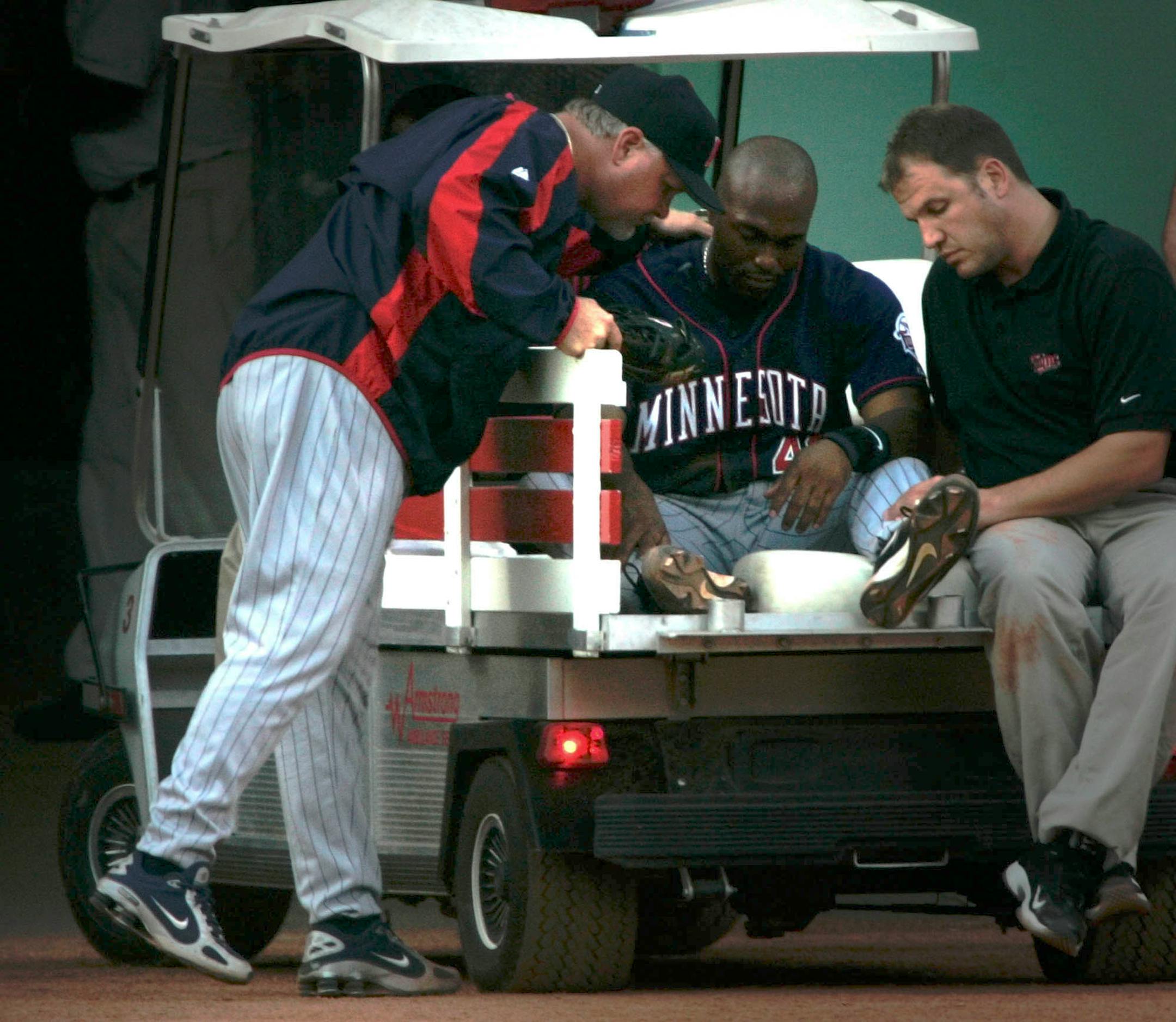 As manager Ron Gardenhire pats him on the back, Minnesota Twins center fielder Torii Hunter is taken from the field on a medical cart after getting injured while chasing a double by Boston Red Sox designated hitter David Ortiz in the first inning at Fenway Park in Boston, Friday, July 29, 2005. (AP Photo/Charles Krupa)