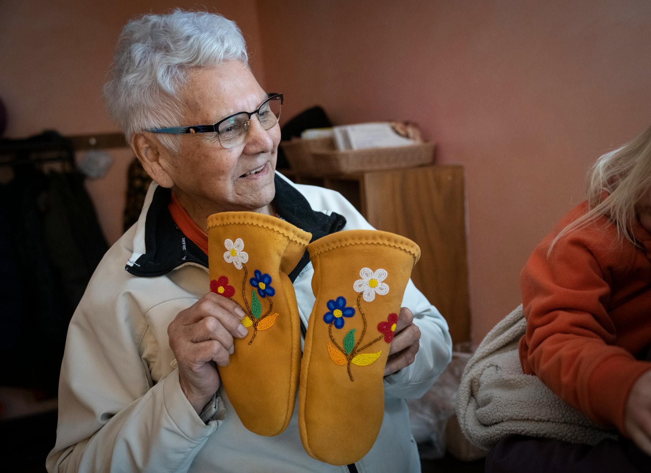 Elder Nigigoonsiminikaaning Nancy Jones offered some sepal mittens to a child as she visited with children as part of the Ojibwe immersion program.