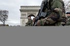 French soldiers cross the Champs Elysees avenue passing the Arc de Triomphe in Paris, Monday, Nov. 16, 2015. France is urging its European partners to