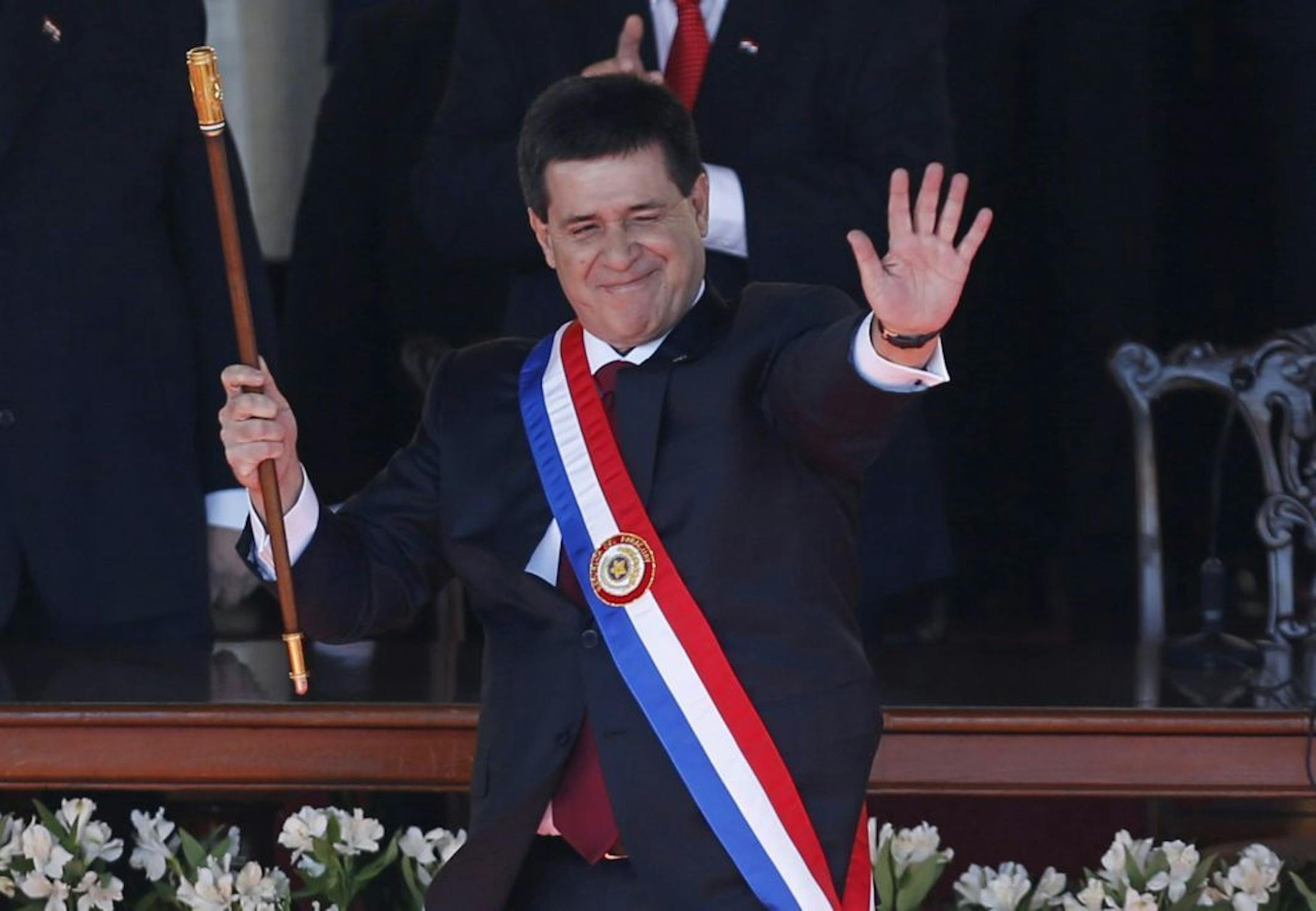 Paraguay's new President Horacio Cartes waves holding the presidential baton and wearing the presidential sash during his swearing-in ceremony at Palacio de Lopez presidential palace in Asuncion, Paraguay, Thursday, Aug. 15, 2013.