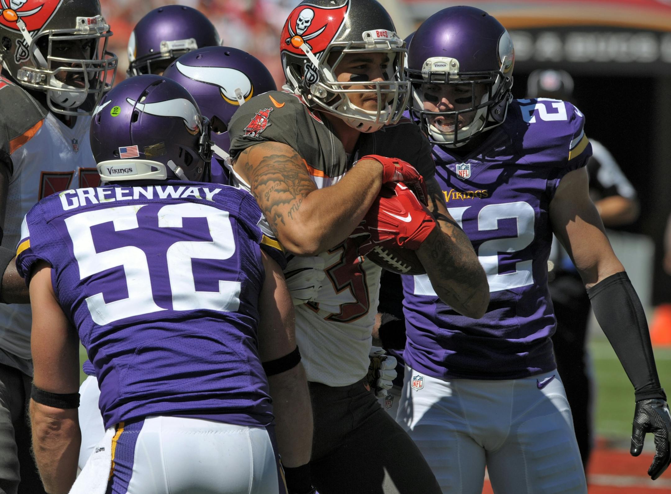 Tampa Bay Buccaneers wide receiver Mike Evans (13) is stopped by Minnesota Vikings free safety Harrison Smith (22) and outside linebacker Chad Greenway (52) after a reception during the first quarter of an NFL football game Sunday, Oct. 26, 2014, in Tampa, Fla.