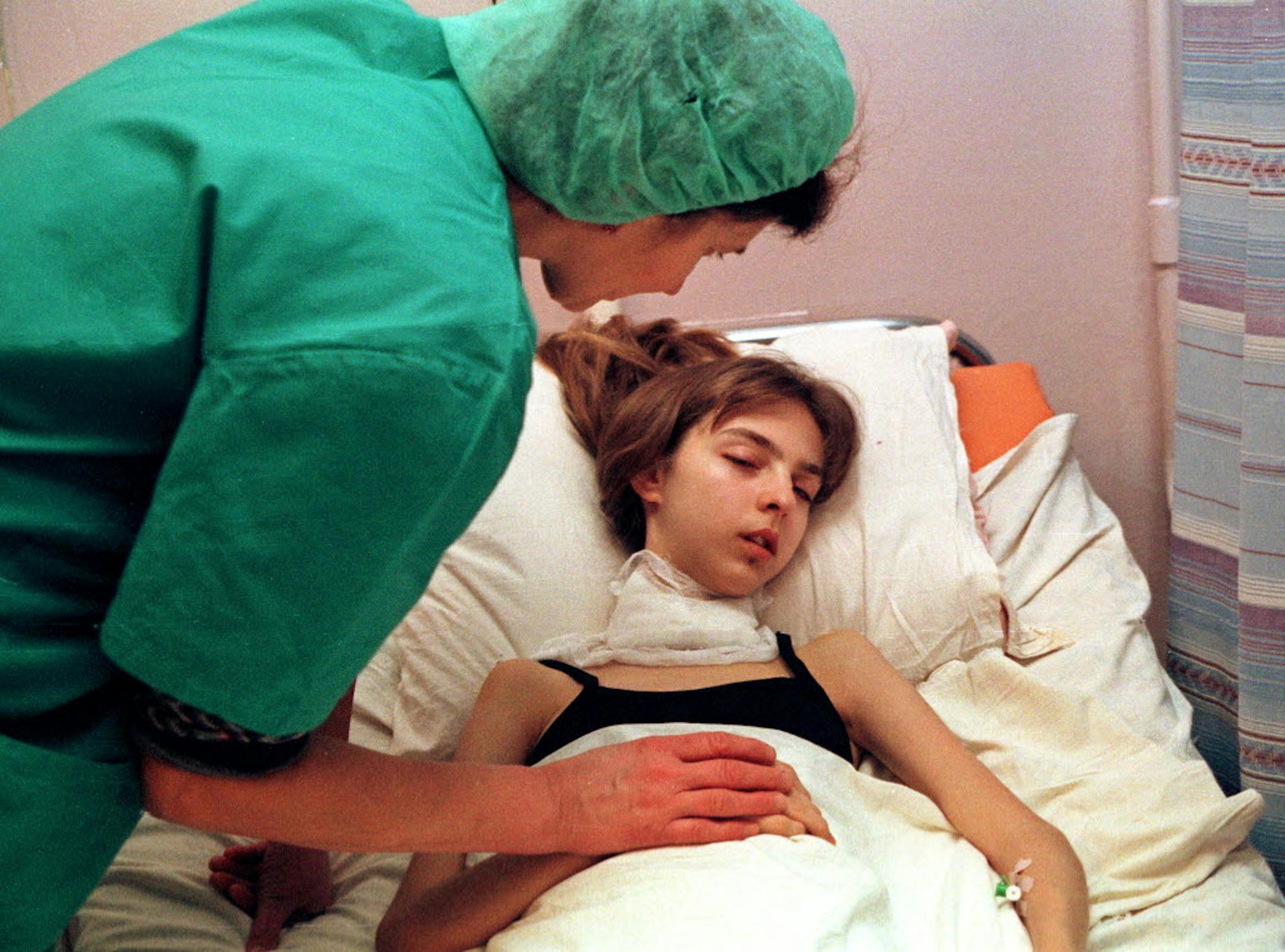 A medical worker bends over a 17-year-old girl who had just undergone thyroid cancer surgery.
