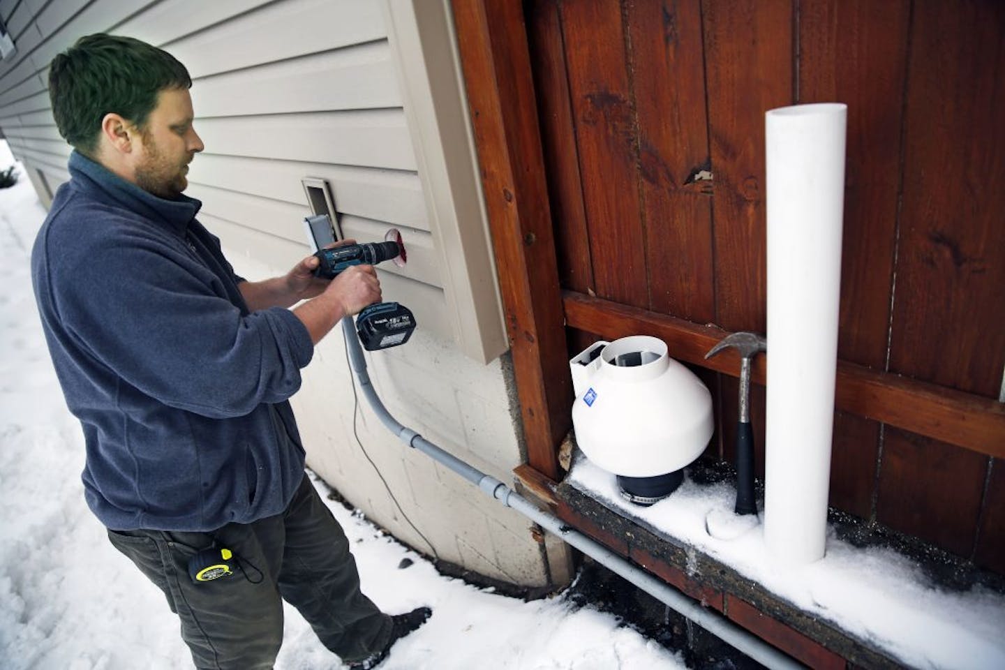 At a home in St. Louis Park, Robert W. Carlson, owner of Healthy Homes drills a hole through the basement wall. The fan on the right is part of a mitigating system that will draw the radon gas out from the basement and evacuate it above the roofline.