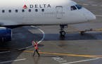 In this Feb. 5, 2019, file photo a ramp worker guides a Delta Air Lines plane at Seattle-Tacoma International Airport in Seattle. (AP Photo/Ted S. War