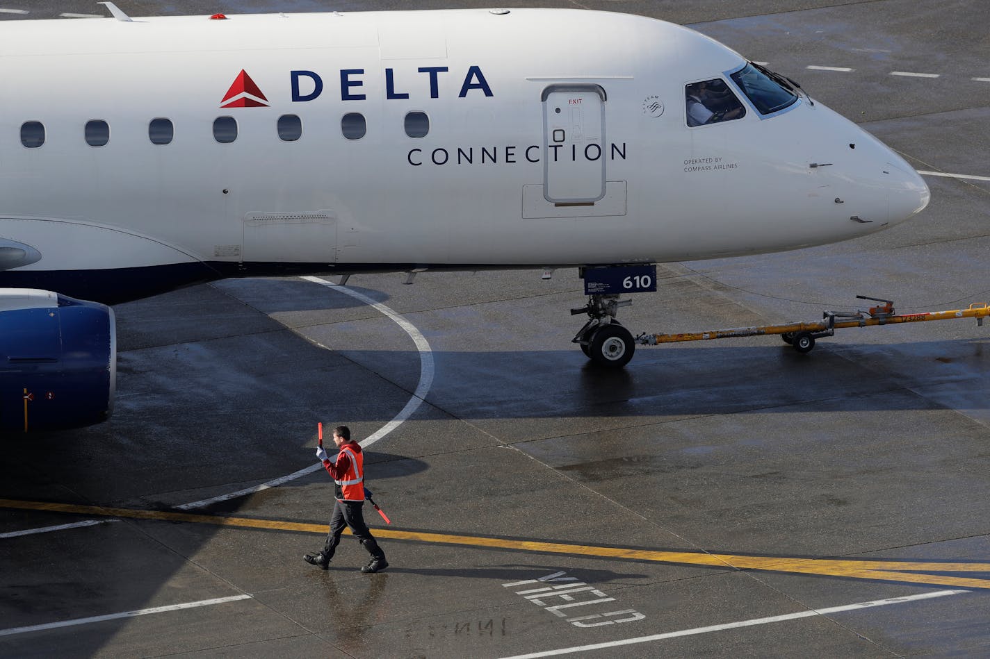 In this Feb. 5, 2019, file photo a ramp worker guides a Delta Air Lines plane at Seattle-Tacoma International Airport in Seattle. (AP Photo/Ted S. Warren, File)