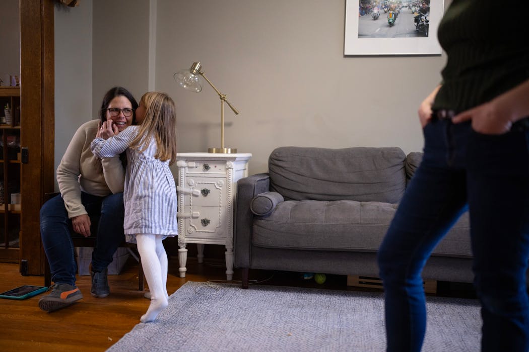 Catherine Sheridan listens to a whispered comment from her daughter as she and her wife, Julianna, played with their kids after dinner. A stay-at-home mom, Catherine says the couple were 