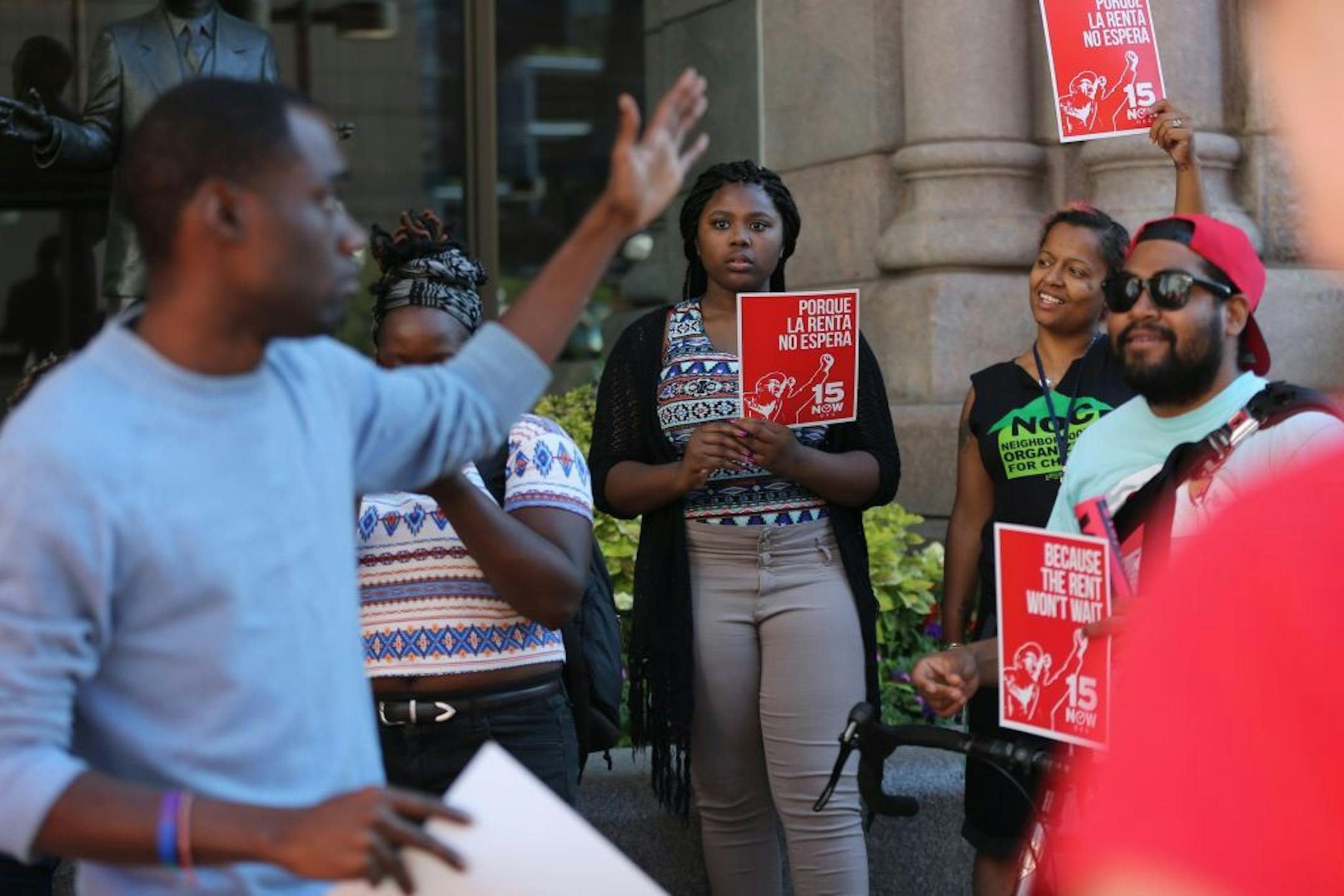 Iyanna Jackson (center) and Tecara Monn listen intently as Mike Griffin, field director at Neighborhoods Organizing for Change, speaks to the crowd gathered outside Minneapolis City Hall to support raising minimum wage to $15 an hour.