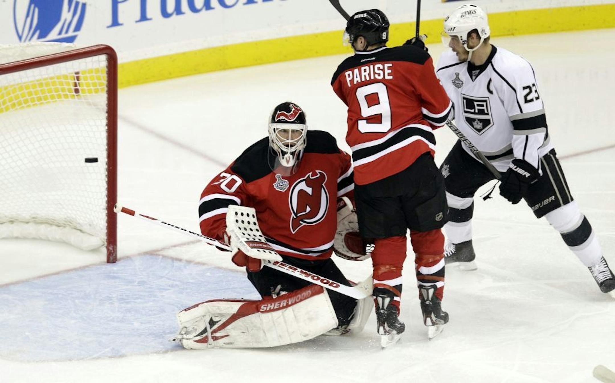 The puck sails past New Jersey Devils' Martin Brodeur into the goal on a shot by Los Angeles Kings' Justin Williams, not shown, in the second period during Game 5 of the NHL hockey Stanley Cup finals, Saturday, June 9, 2012, in Newark, N.J.. New Jersey Devils' Zach Parise and Los Angeles Kings' Dustin Brown were nearby.