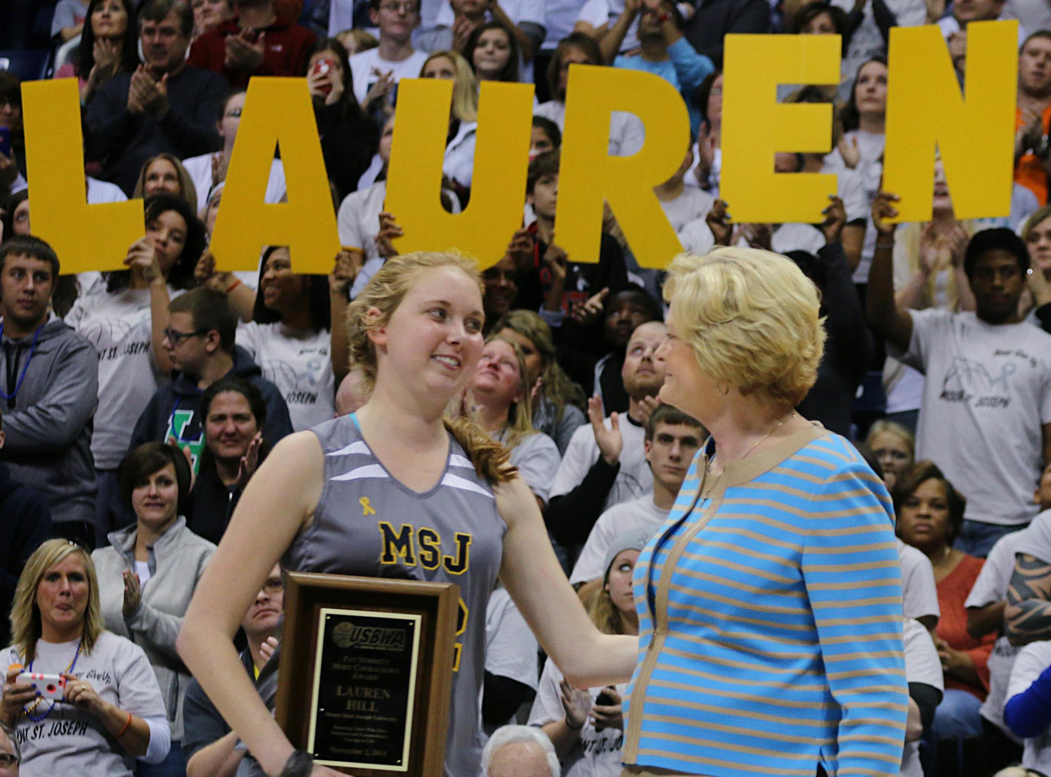 Mount St. Joseph's Lauren Hill hugs Pat Summit after receiving the Pat Summitt Award during halftime of her first NCAA college basketball game against Hiram University at Xavier University in Cincinnati on Sunday, Nov. 2, 2014. The NCAA allowed Mount St. Joseph's season opener to be moved up to Nov. 2, so that Hill, who has an inoperable brain tumor, to be able to play in a college basketball game. WNBA Player Tamika Devonne Catchings, of the Indiana Fever is at the right. (AP Photo/Tom Uhlman)