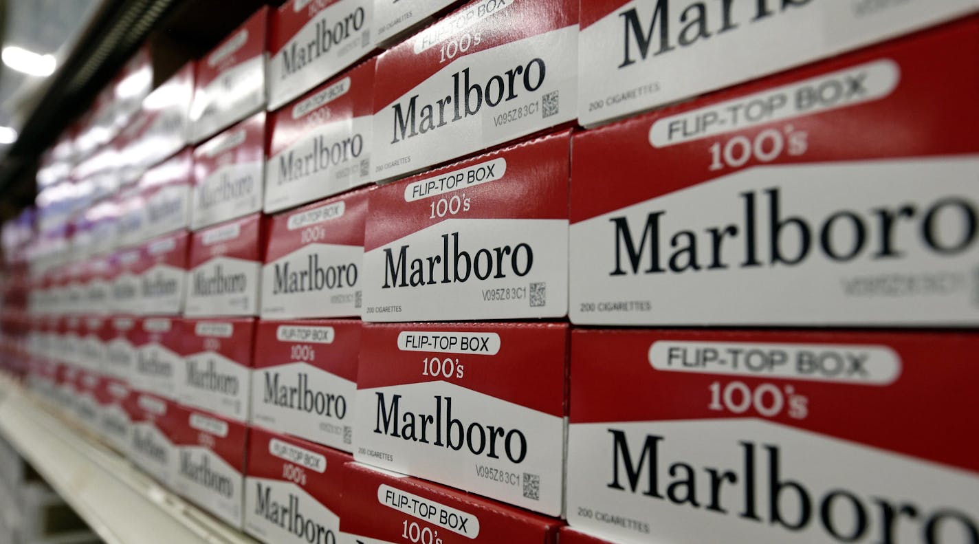 FILE- This June 14, 2018, file photo shows cartons of Marlboro cigarettes on the shelves at JR outlet in Burlington, N.C. Altria confirmed Tuesday, Aug. 27, 2019, that it is in talks to merge with Philip Morris International more than a decade after splitting itself into two companies. Altria has exclusively sold Marlboro and other cigarette brands in the U.S., while Philip Morris has handled international sales. (AP Photo/Gerry Broome, File)