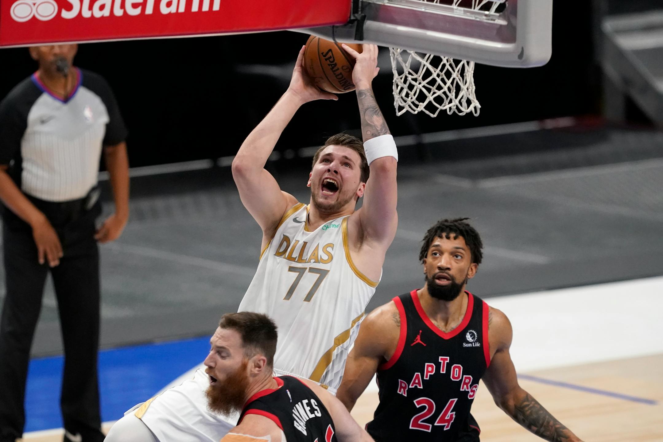 Dallas Mavericks guard Luka Doncic (77) takes a shot as Toronto Raptors' Aron Baynes, left, and Khem Birch (24) defend in the first half of an NBA basketball game in Dallas, Friday, May 14, 2021. (AP Photo/Tony Gutierrez)