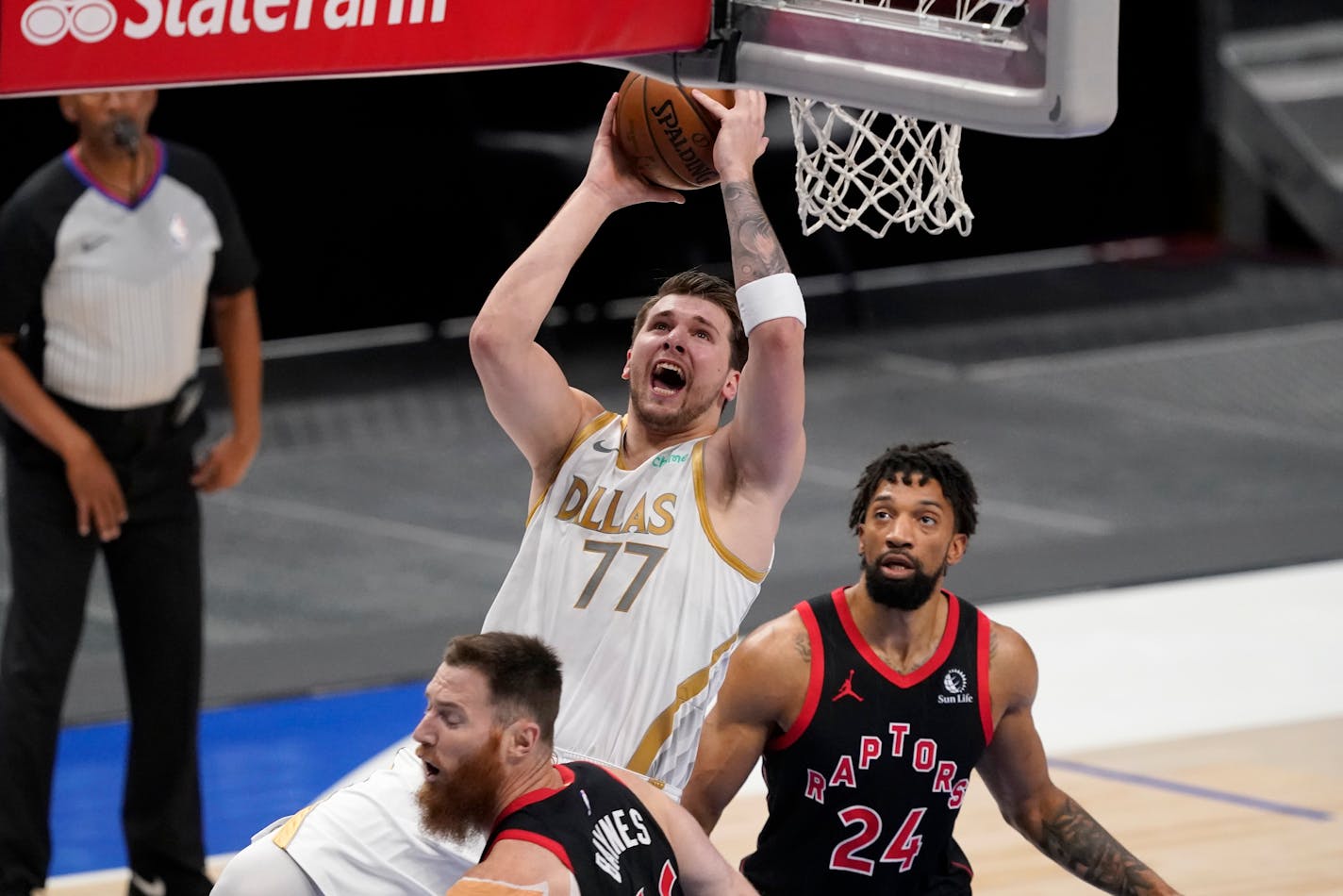 Dallas Mavericks guard Luka Doncic (77) takes a shot as Toronto Raptors' Aron Baynes, left, and Khem Birch (24) defend in the first half of an NBA basketball game in Dallas, Friday, May 14, 2021. (AP Photo/Tony Gutierrez)