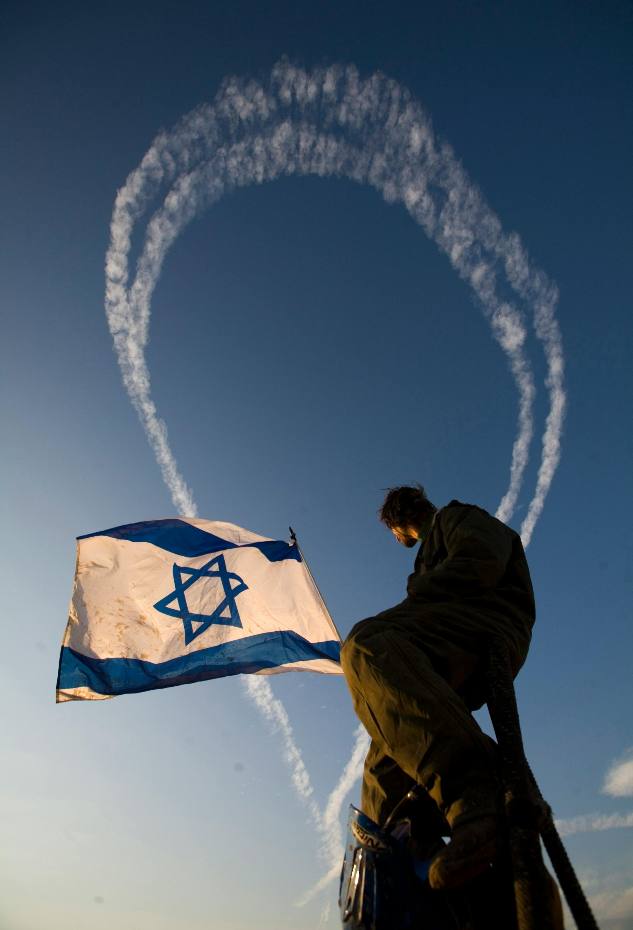 An Israeli watches fighter planes fly over the northern Gaza Strip as seen from the Israeli side of the border with Gaza, Saturday, Jan. 3, 2009. Israeli warplanes, gunboats and artillery units blasted more than 40 Hamas targets Saturday, including weapons storage facilities, training centers and leaders' homes as Israel's offensive against Gaza's Islamic militant rulers entered a second week.