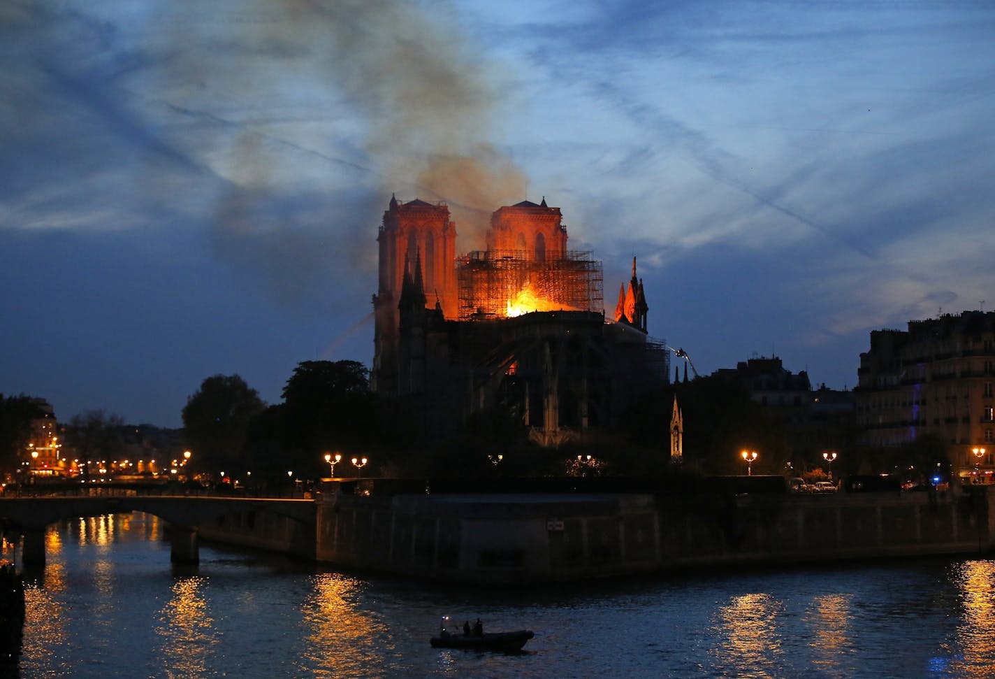 Firefighters tackle the blaze as flames and smoke rise from Notre Dame cathedral as it burns in Paris, Monday, April 15, 2019. Massive plumes of yellow brown smoke is filling the air above Notre Dame Cathedral and ash is falling on tourists and others around the island that marks the center of Paris.