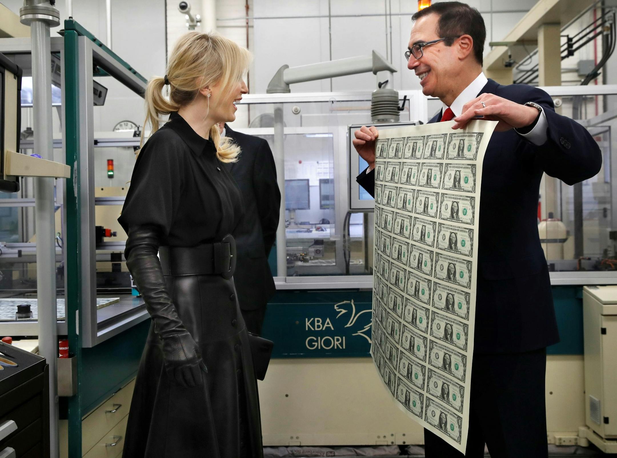 Treasury Secretary Steven Mnuchin, right, and his wife Louise Linton, left, react as Mnuchin holds up a sheet of new $1 bills, the first currency notes bearing his and U.S. Treasurer Jovita Carranza's signatures, Wednesday, Nov. 15, 2017, at the Bureau of Engraving and Printing in Washington. The Mnuchin-Carranza notes, which are a new series of 2017, 50-subject $1 notes, will be sent to the Federal Reserve to issue into circulation. (AP Photo/Jacquelyn Martin) ORG XMIT: DCJM101
