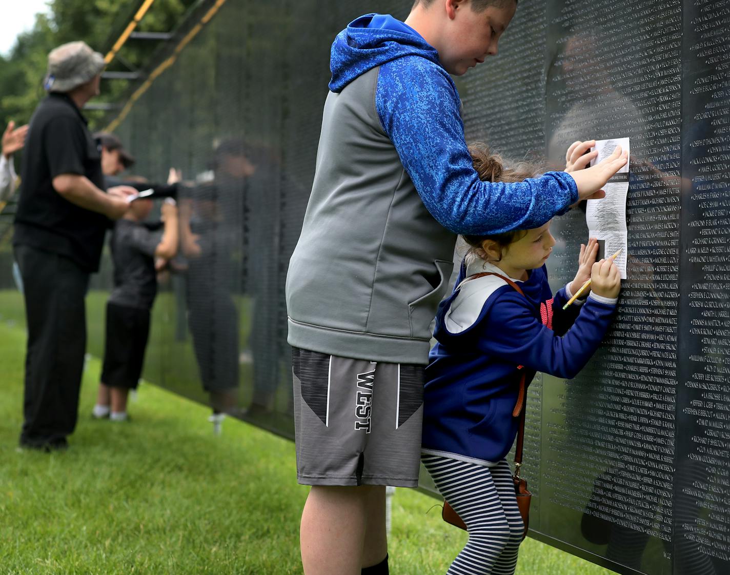 Scarlett Nagorski, 5, of Belle Plaine, got help from her brother Pierce, 11, as she etched names of Vietnam vets killed in the war onto a piece of paper Thursday. They were visiting a traveling replica of the Washington, D.C., memorial at the Minnesota Capitol. Their father Jeremy Nagorski recently retired from the Army National Guard.