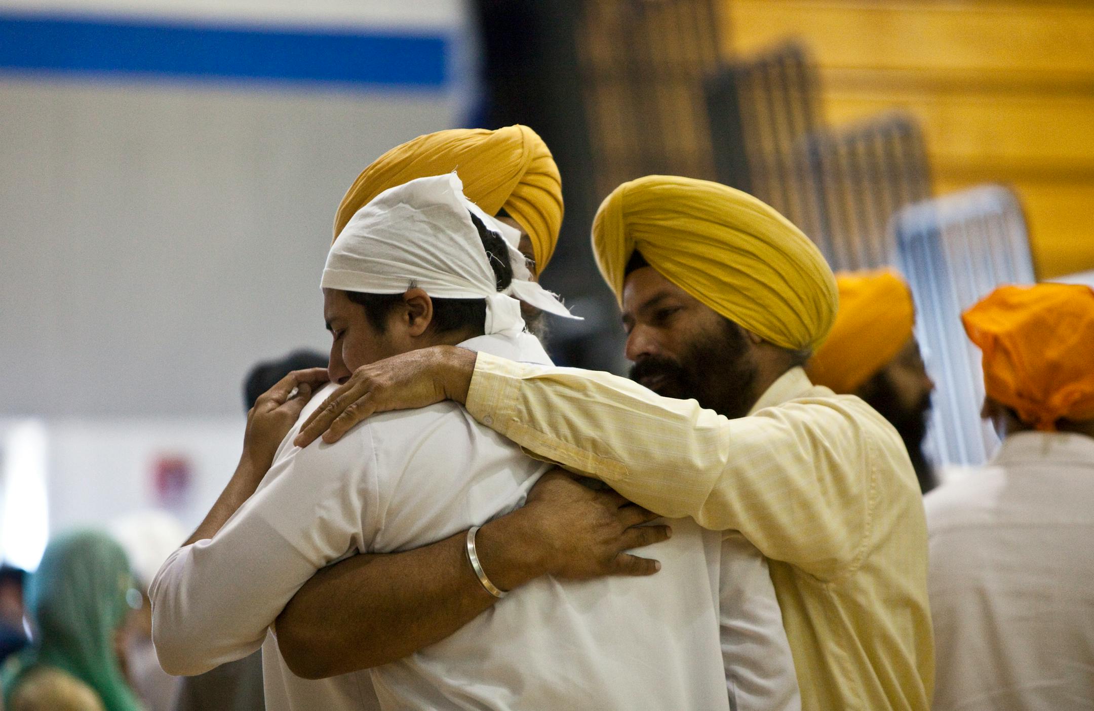 Mourners embrace during wake and visitation services for the six victims of the Sikh temple shooting at the Oak Creek High School gymnasium in Oak Creek, Wis., Aug. 10, 2012.