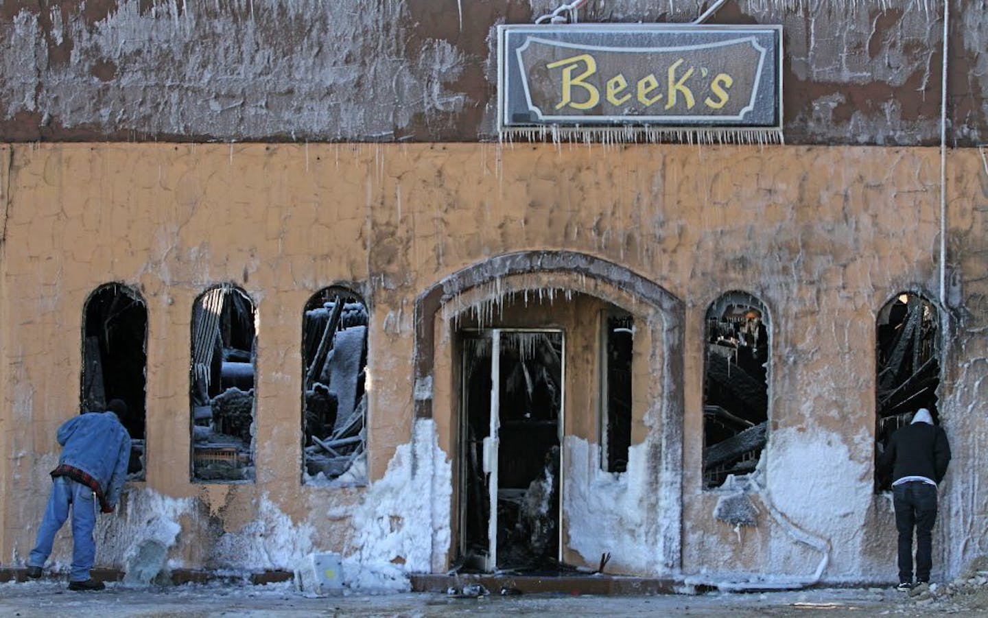 People looked into the building that housed Beek's Pizza and Diamond Lake Rental on Friday in south Minneapolis after a fire Thursday.