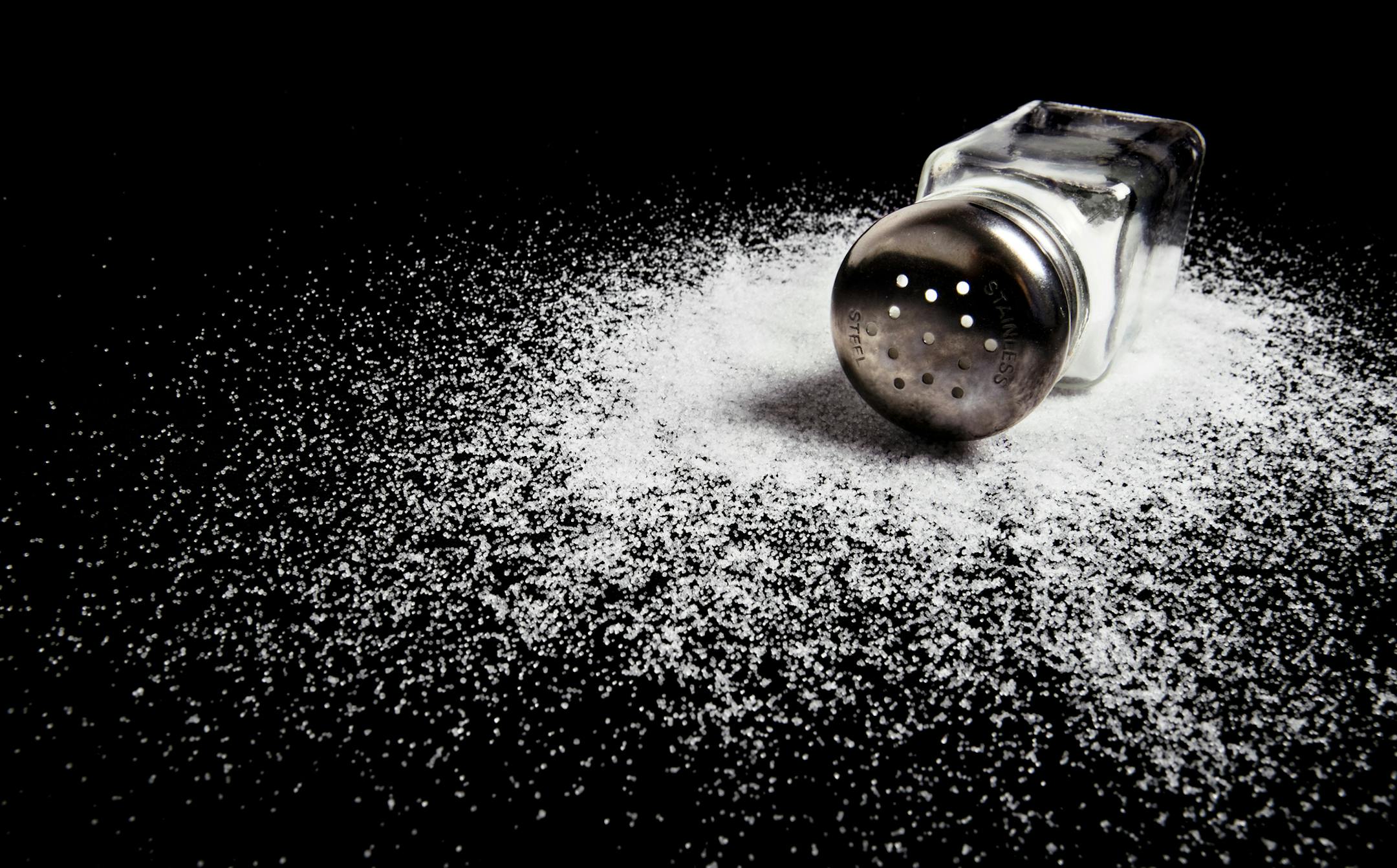 A spilled salt shaker on a black background.