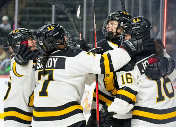 Warroad forward Rylee Bartz (6) is embraced by her teammates after scoring a goal in the first period of the Class 1A girl's hockey championship Satur