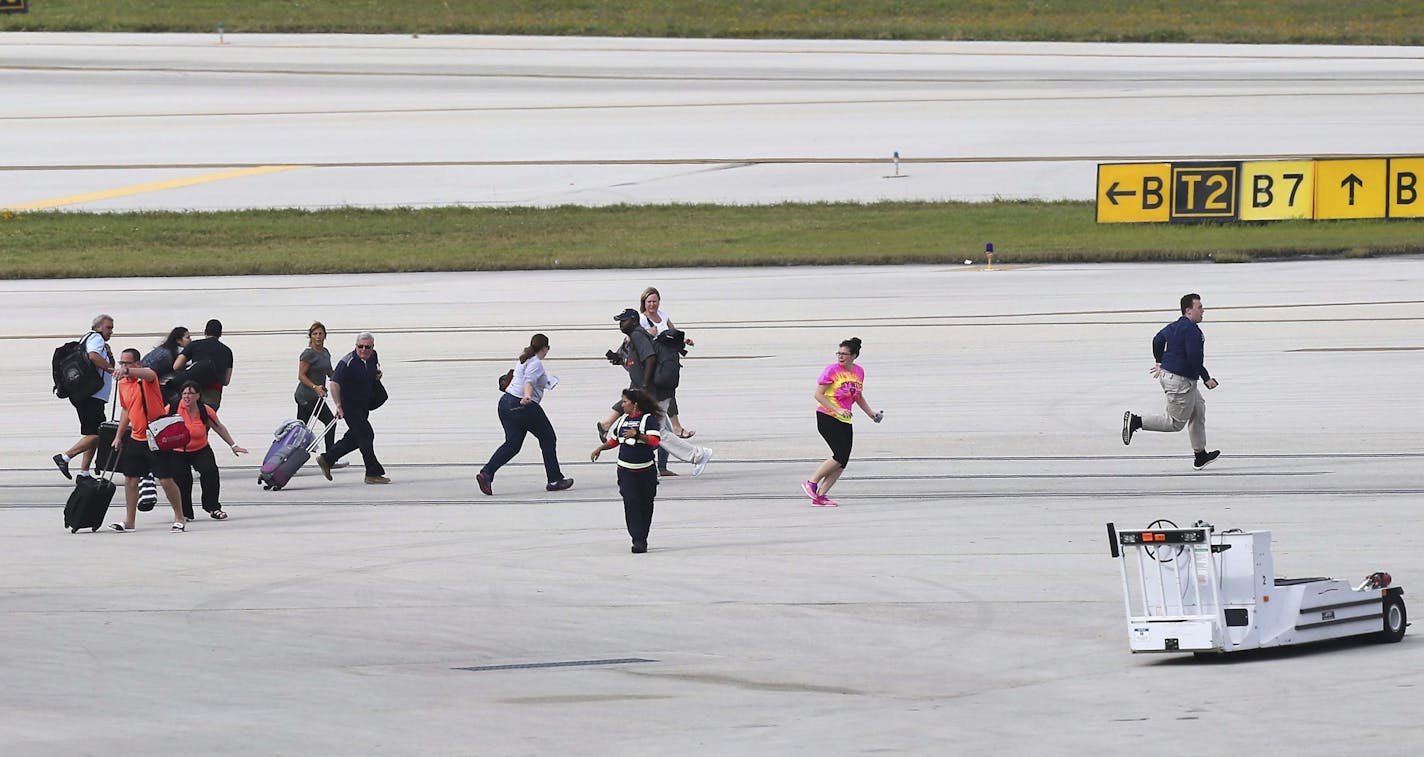 Passengers run on the tarmac at Fort Lauderdale-Hollywood International Airport, Friday, Jan. 6, 2017, in Fort Lauderdale, Fla. A gunman opened fire in the baggage claim area at the airport Friday, killing several people and wounding others before being taken into custody in an attack that sent panicked passengers running out of the terminal and onto the tarmac, authorities said.