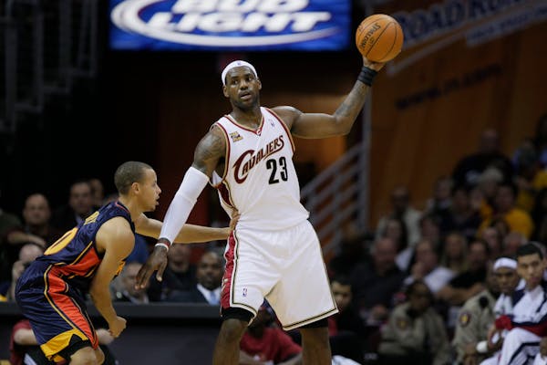 Cleveland Cavaliers' LeBron James (23) keeps the ball away from Golden State Warriors' Stephen Curry in 2009.
