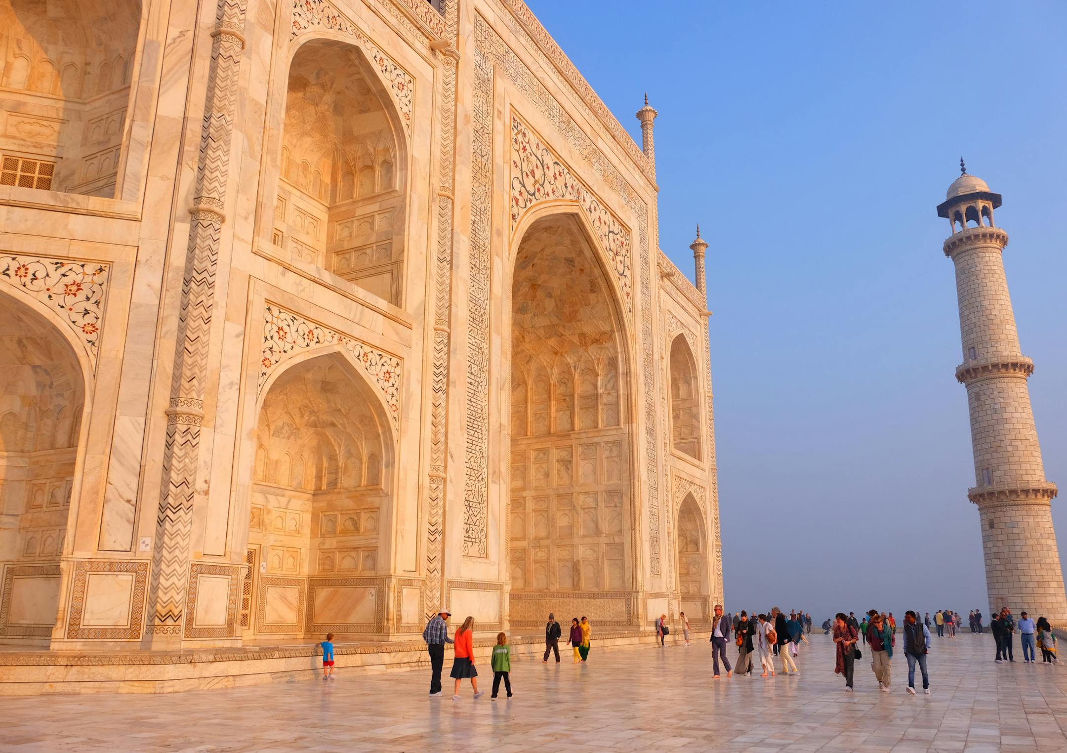 The soaring walls of the Taj Mahal glowed at sunrise, the best time to visit, and dwarfed tourists walking below in bare feet or with shoe coverings to protect the light stone of the monument.