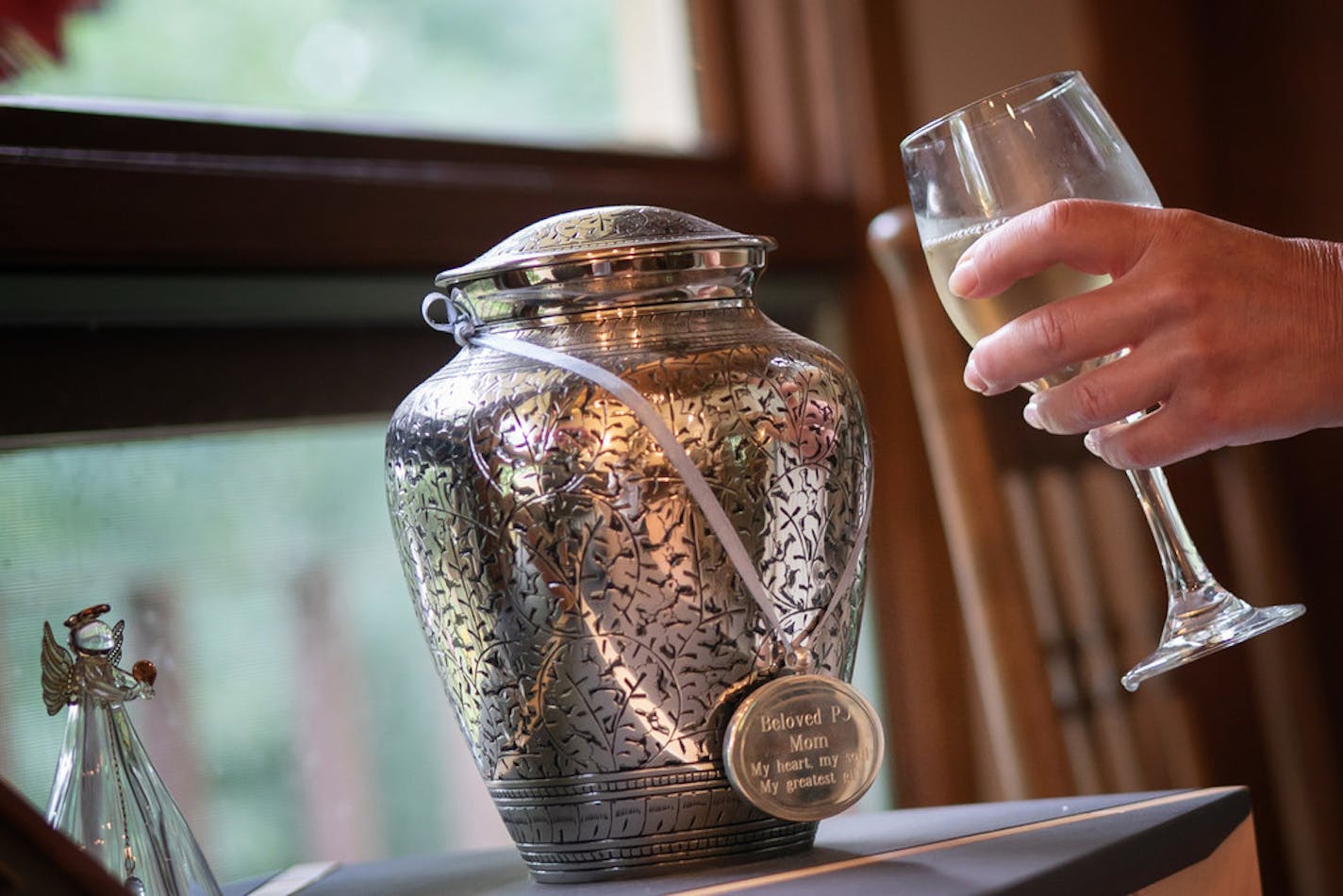 At night, after finishing her writing for the day, Traci Lambrecht toasts the urn with the ashes of her mother, P.J. Lambrecht.