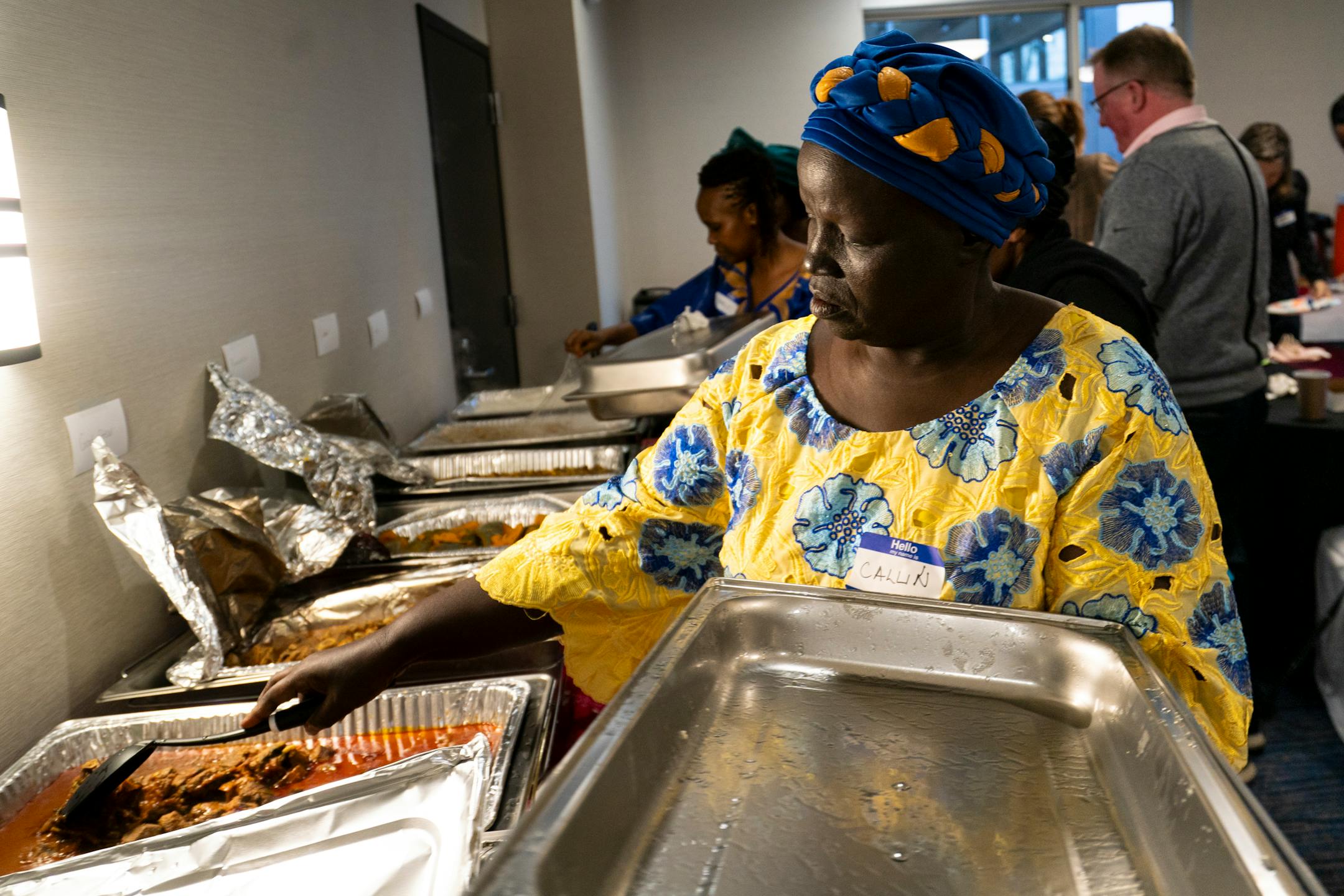 Callin Bosire opens the beef stew dish at the end-of-season harvest festival hosted by the Minnesota African Immigrant Farmer Association (MAIFA) in Maple Grove, Minn. on Sunday, Dec. 3, 2023. This is MAIFA's first annual harvest festival celebrating emerging, first-generation, and African farmers bringing Africa's diverse vegetables and crops to Minnesota. Farmers from across Minnesota and from a variety of countries in Africa brought their freshly-farmed food to the table. ] Angelina Katsanis • angelina.katsanis@startribune.com