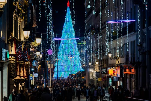People walk past Christmas lights in downtown Madrid, Spain, Tuesday, Dec. 21, 2021. Despite vaccination rates that make other governments envious, Spain and Iberian neighbor Portugal are facing the hard truth that these winter holidays won't be a time of unrestrained joy. The reason is the new omicron variant that has been running rampant across Europe. (AP Photo/Bernat Armangue)