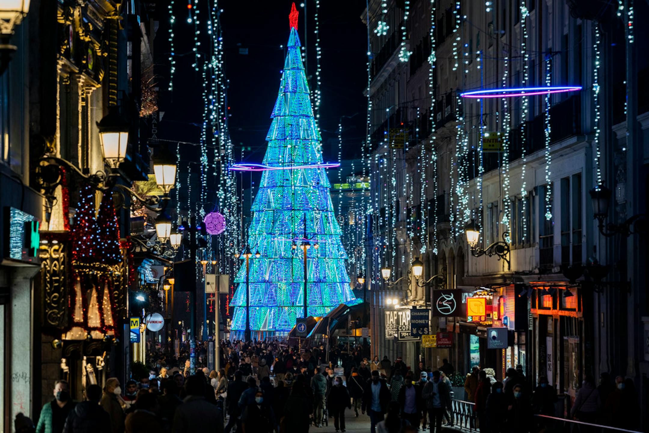 People walk past Christmas lights in downtown Madrid, Spain, Tuesday, Dec. 21, 2021. Despite vaccination rates that make other governments envious, Spain and Iberian neighbor Portugal are facing the hard truth that these winter holidays won't be a time of unrestrained joy. The reason is the new omicron variant that has been running rampant across Europe. (AP Photo/Bernat Armangue)